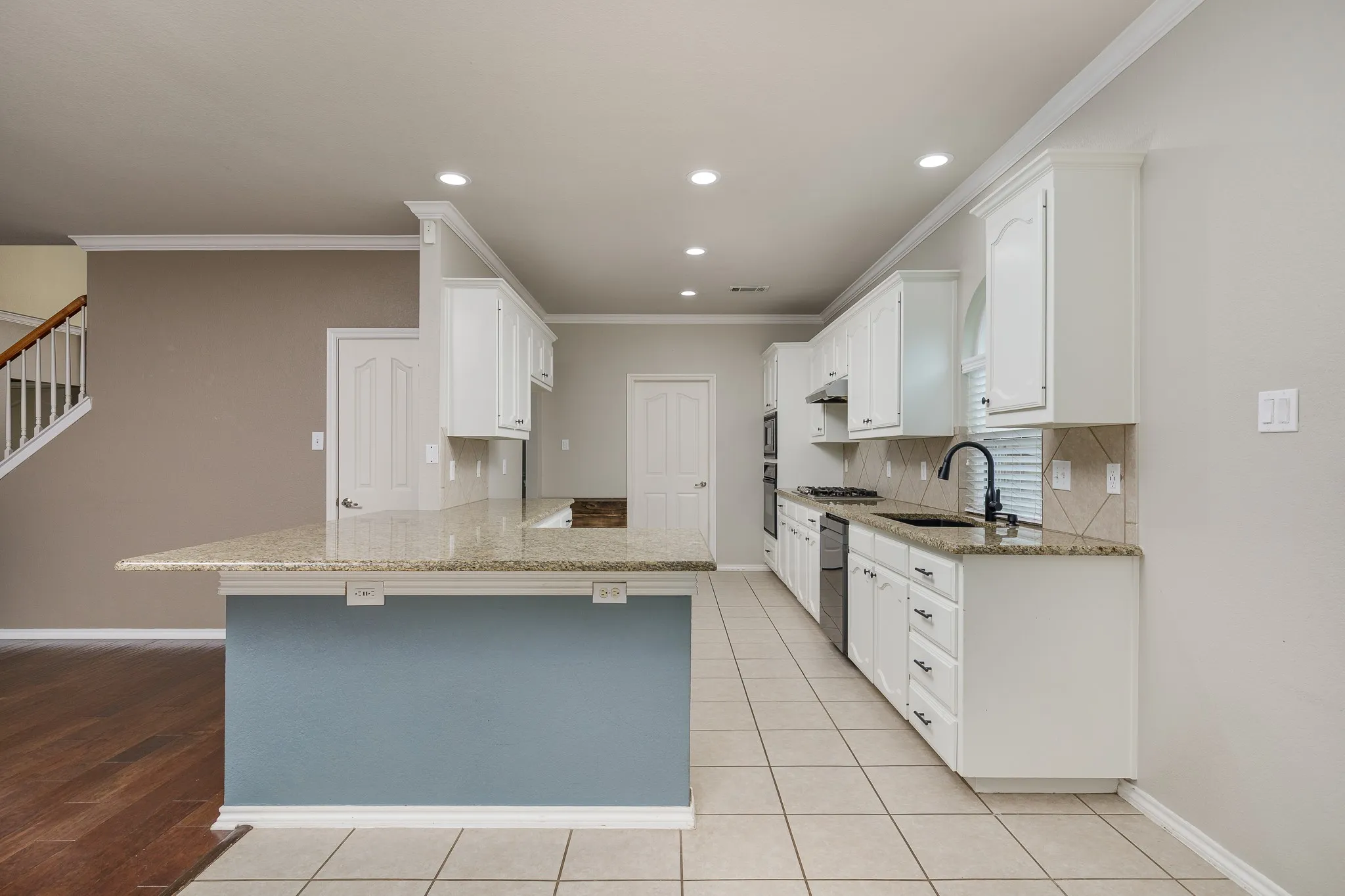 Modern kitchen featuring white cabinetry, granite countertops, a tile backsplash, stainless steel appliances, and recessed lighting