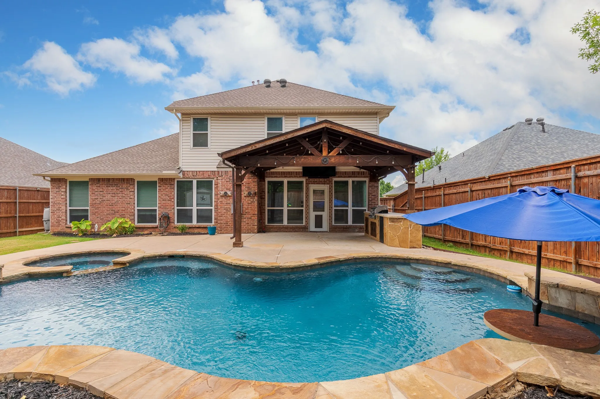 Resort-style backyard featuring a freeform swimming pool with integrated spa and stone coping
