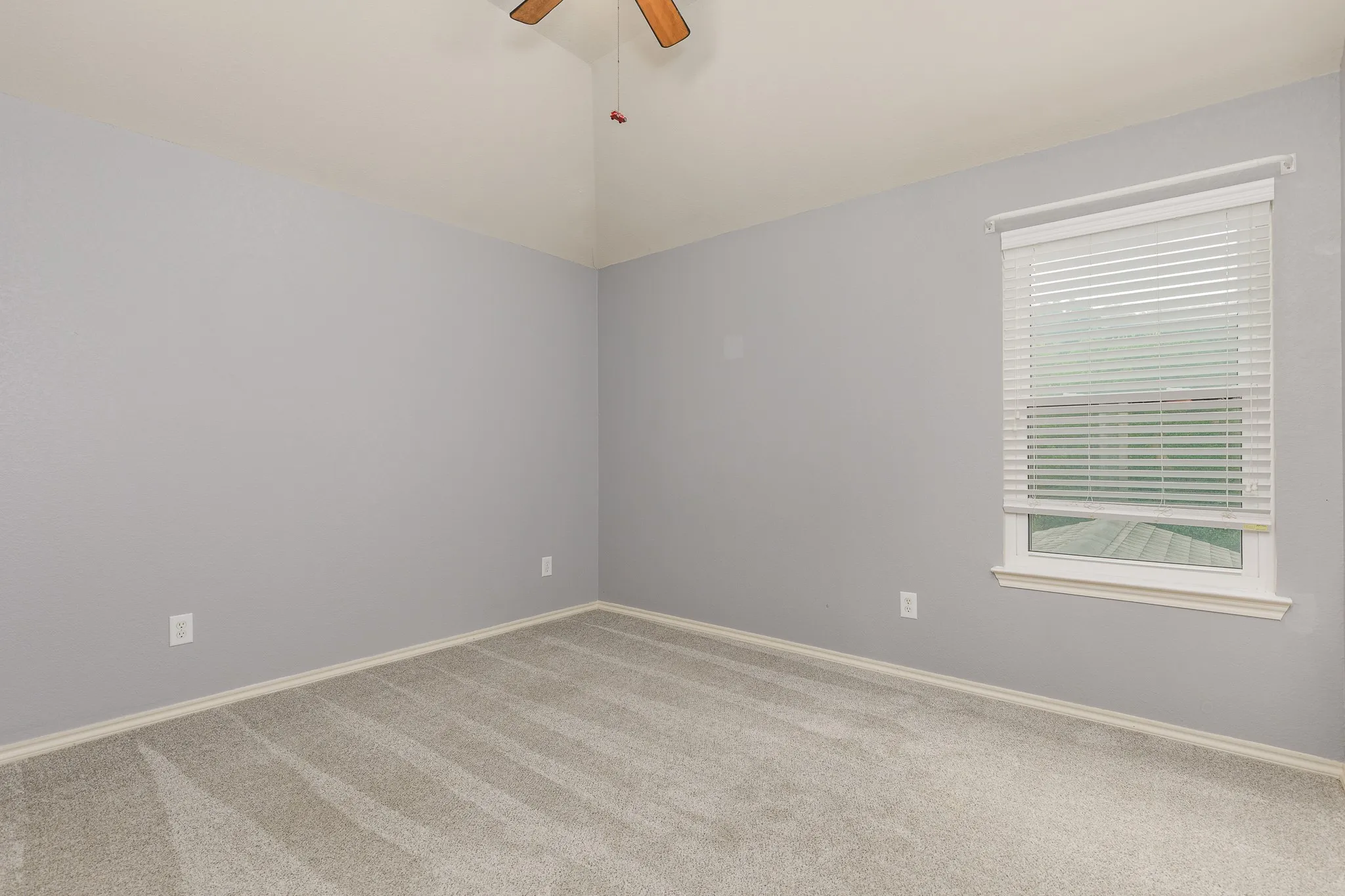 Vaulted ceiling room featuring light grey walls and plush carpet flooring