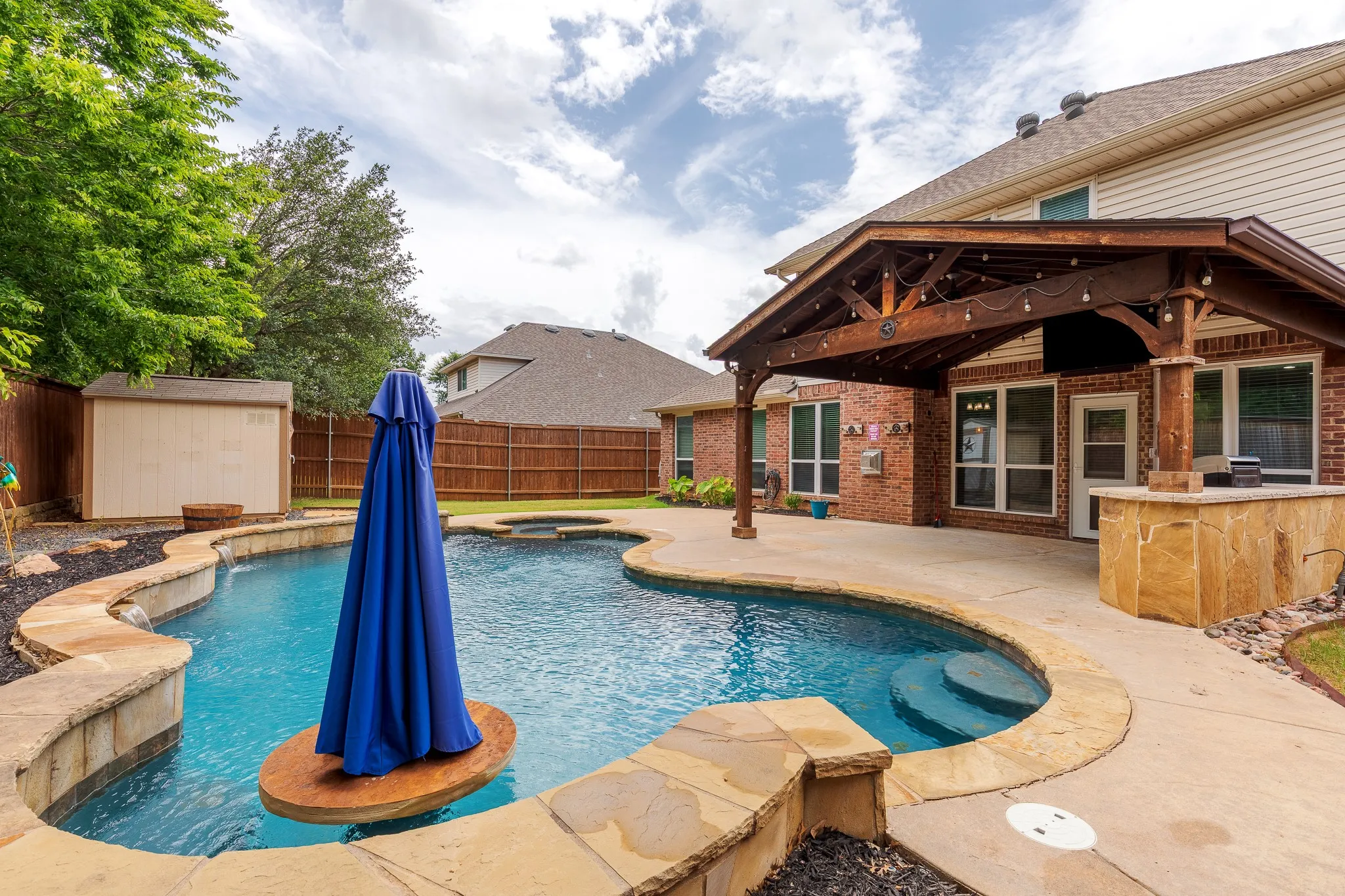 Expansive backyard featuring a custom-shaped swimming pool with stone coping and integrated spa