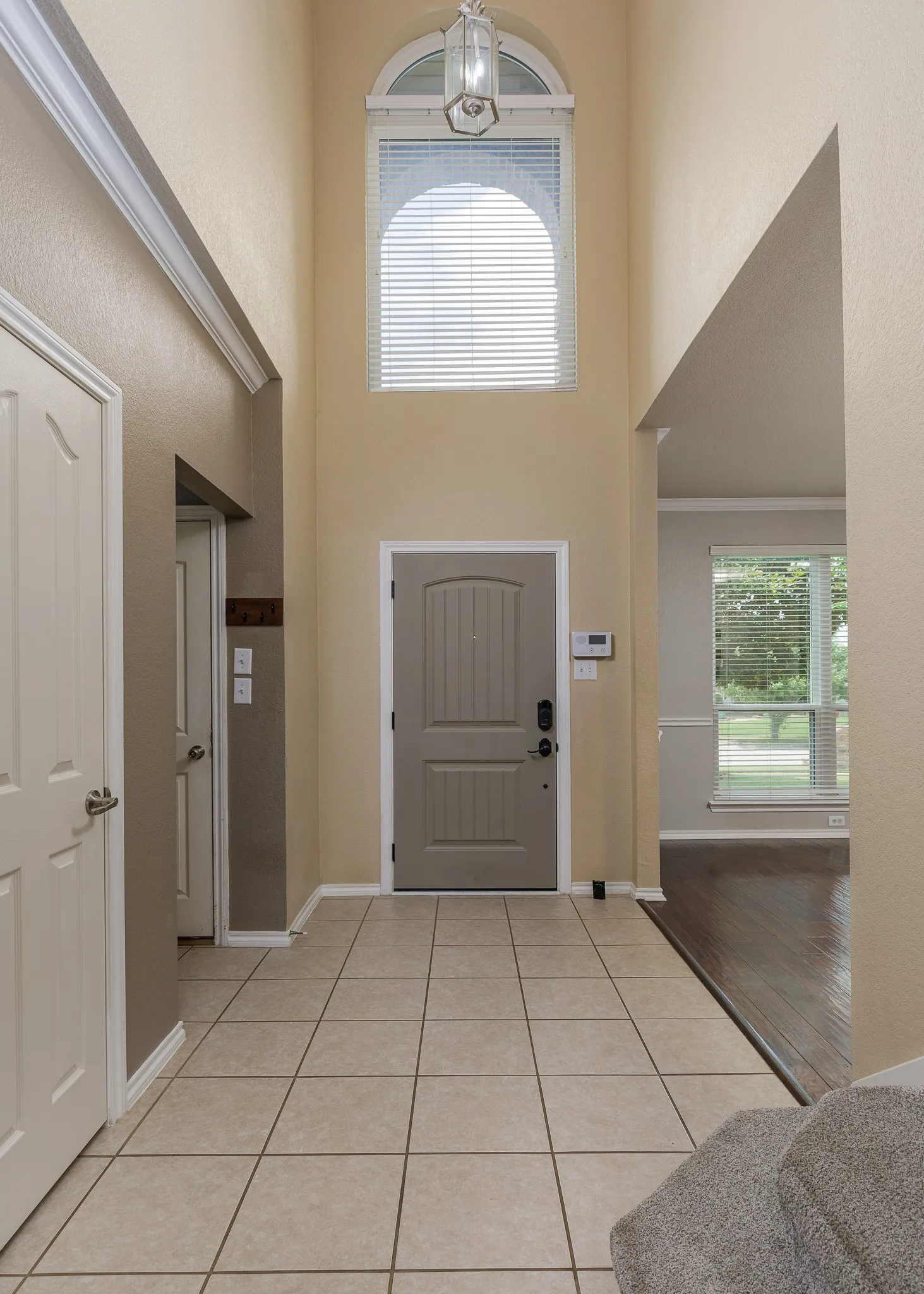 Two-story entry foyer featuring a vaulted ceiling and an arched window with blinds
