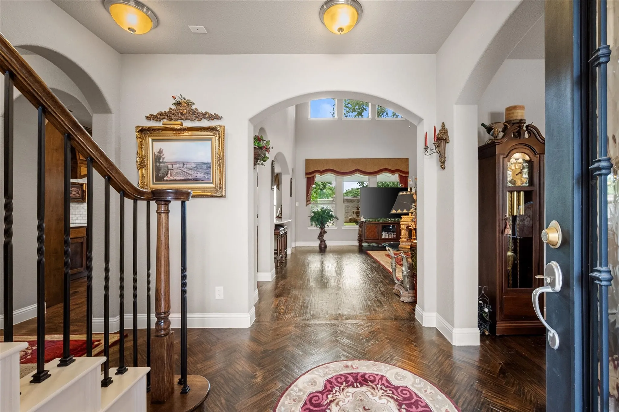 Iron and glass front door welcomes you into a grand entry showcasing exquisite herringbone-pattern hand-scraped hardwood flooring.