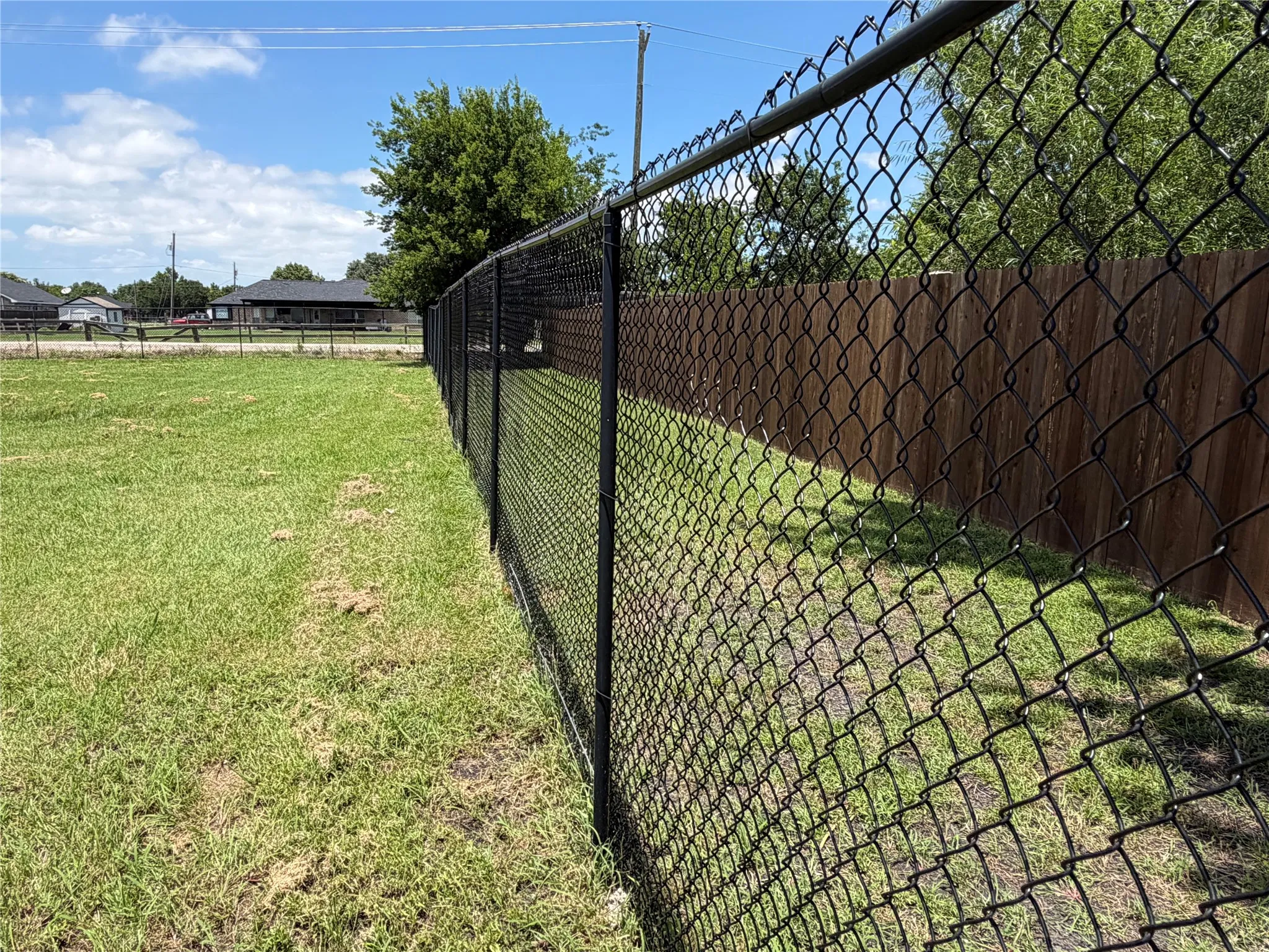 Black chain-link fencing bordering a wood privacy fence