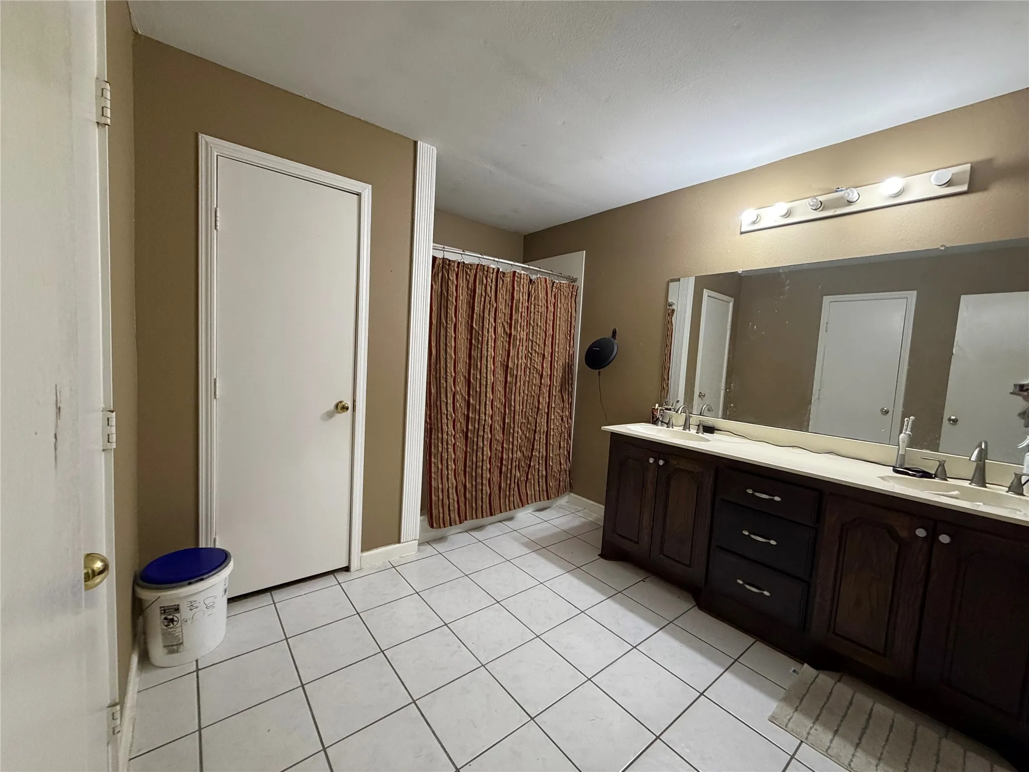 Bathroom featuring a dual vanity with dark wood cabinetry, a light-colored countertop, and a full-width wall mirror
