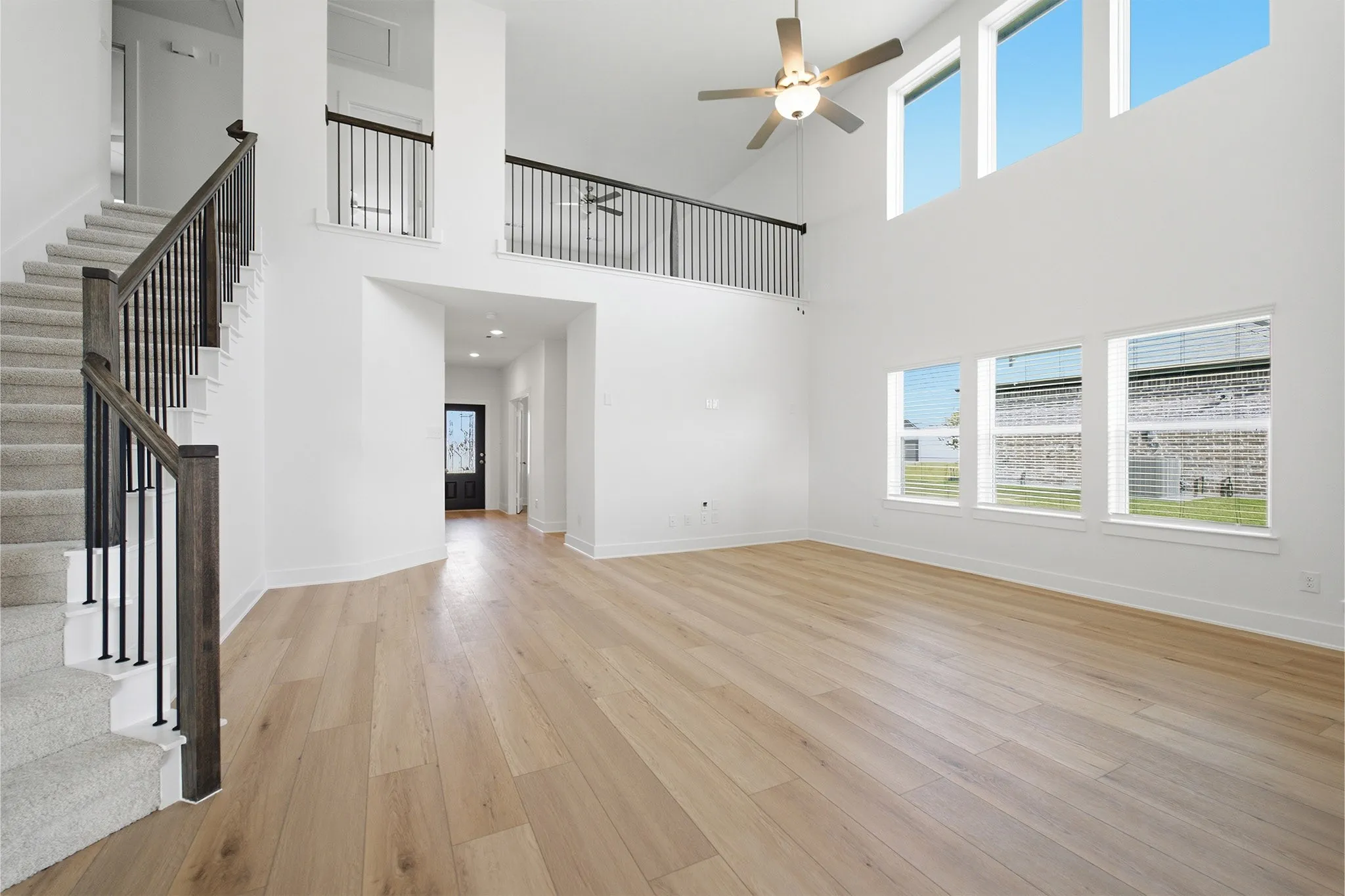 Spacious living area featuring high ceilings, wood-finish flooring, and multiple large windows