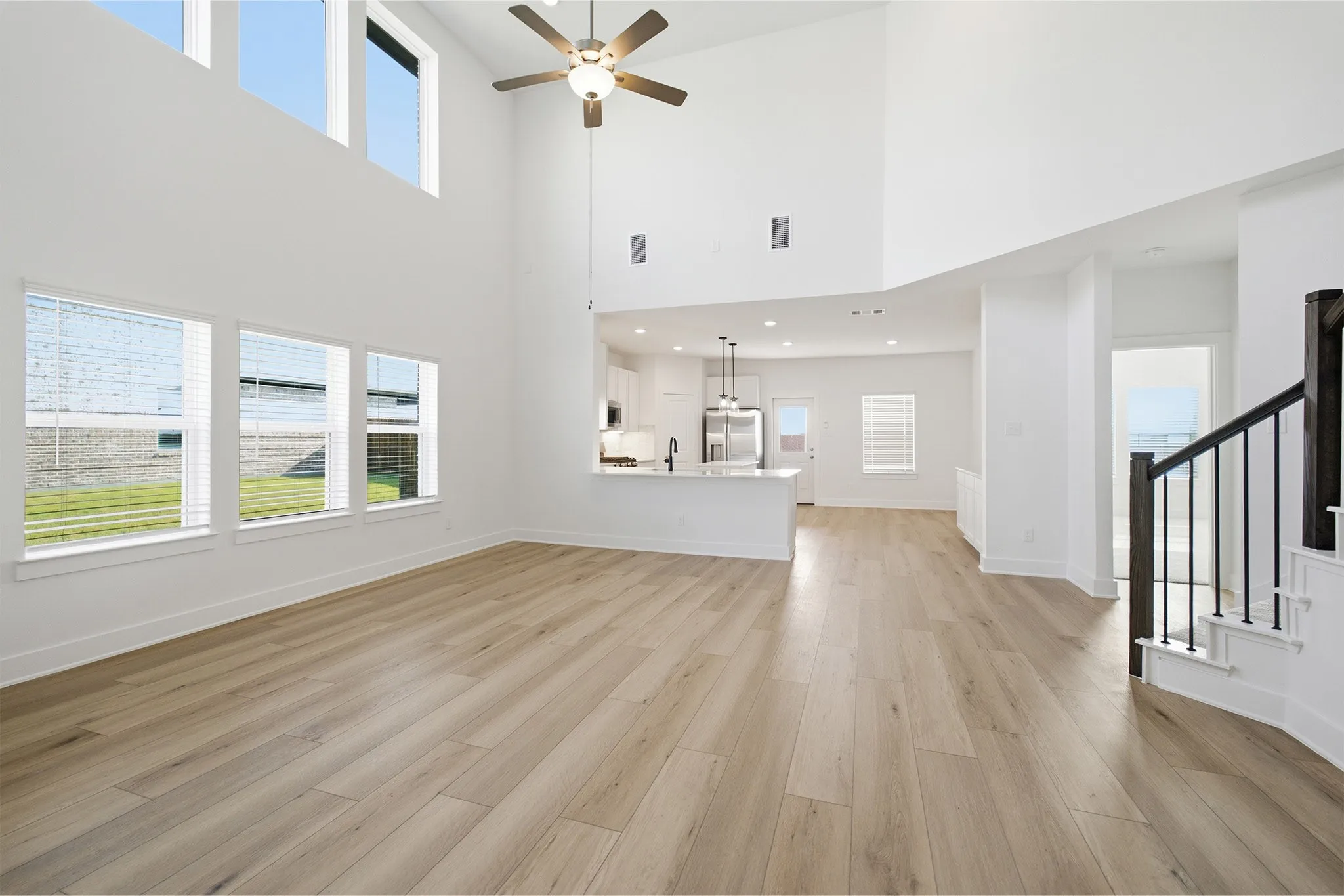 Spacious living area featuring high ceilings, wood-finish flooring, and multiple windows