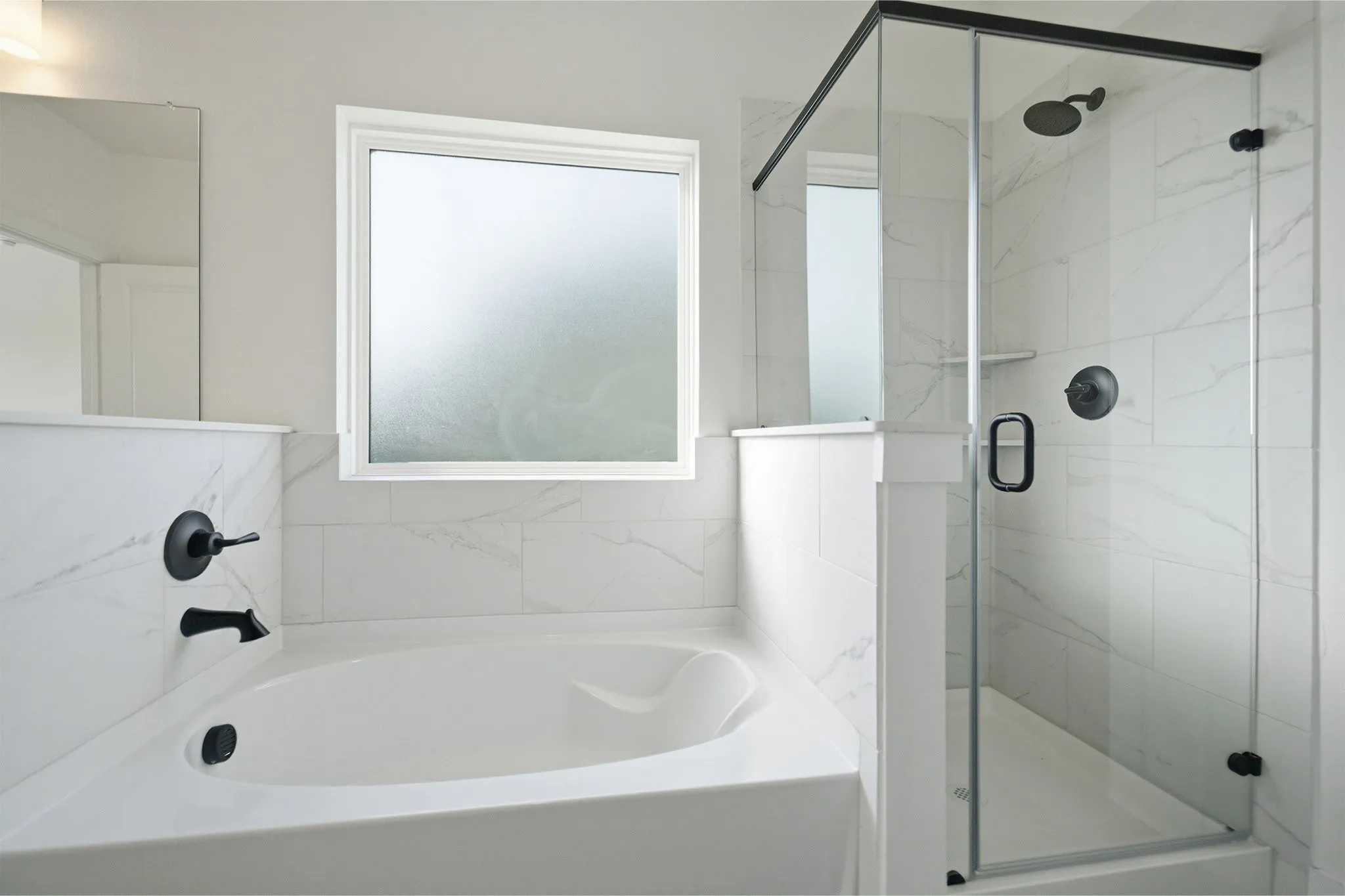 Soaking tub and glass-enclosed shower featuring matte black fixtures