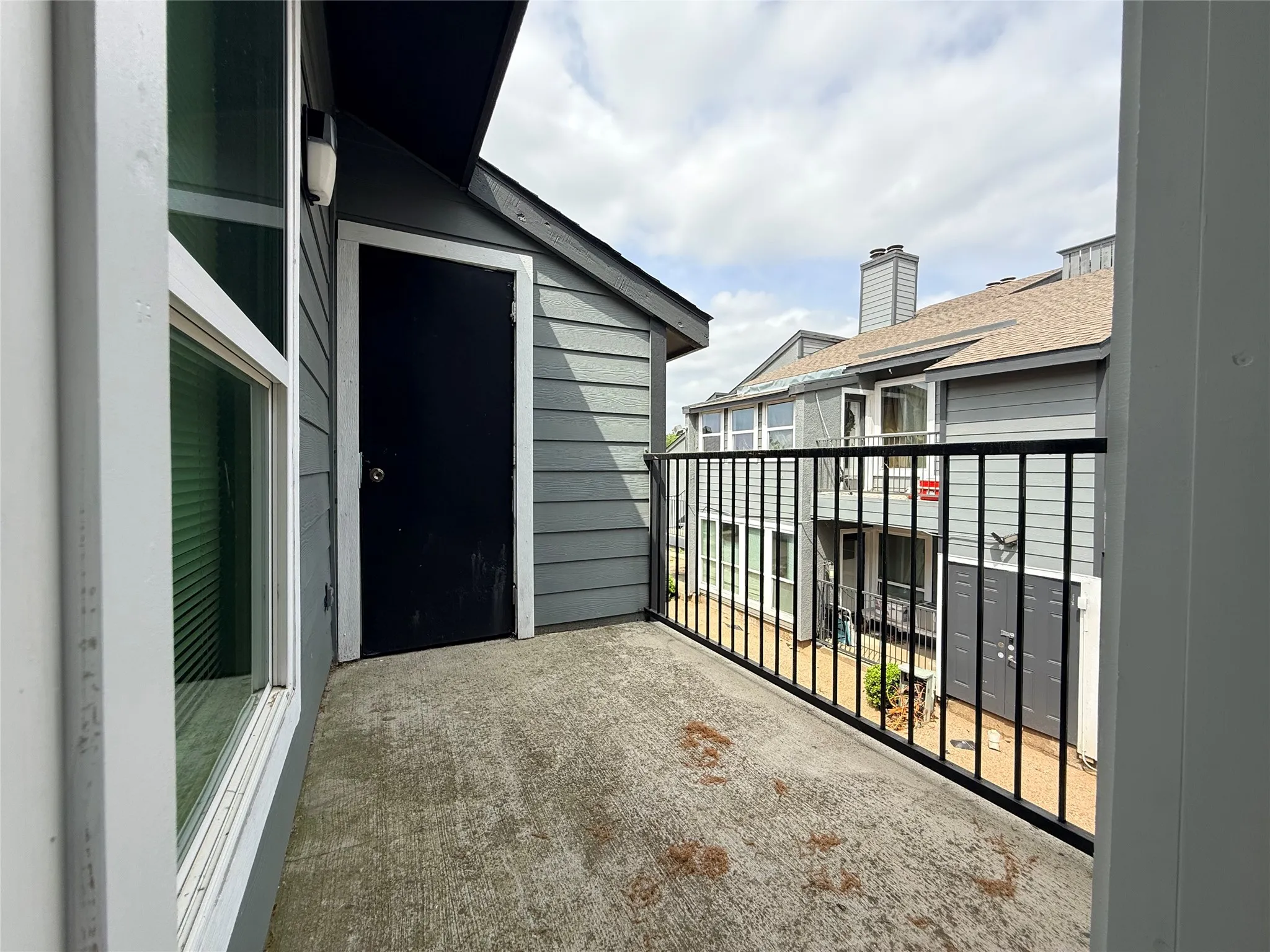 Private balcony featuring a concrete surface, black metal railing, and exterior storage closet