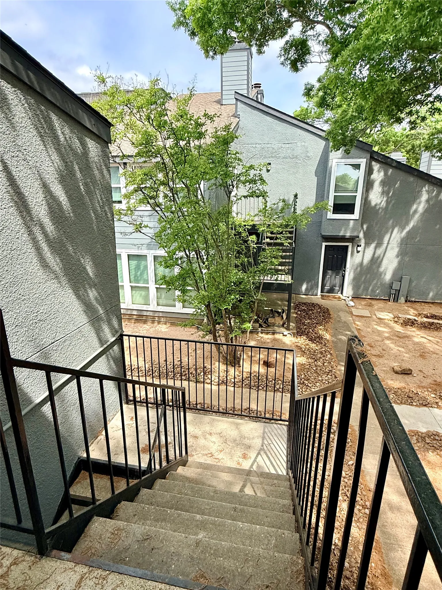 Exterior concrete staircase with black metal railings leading to a fenced courtyard