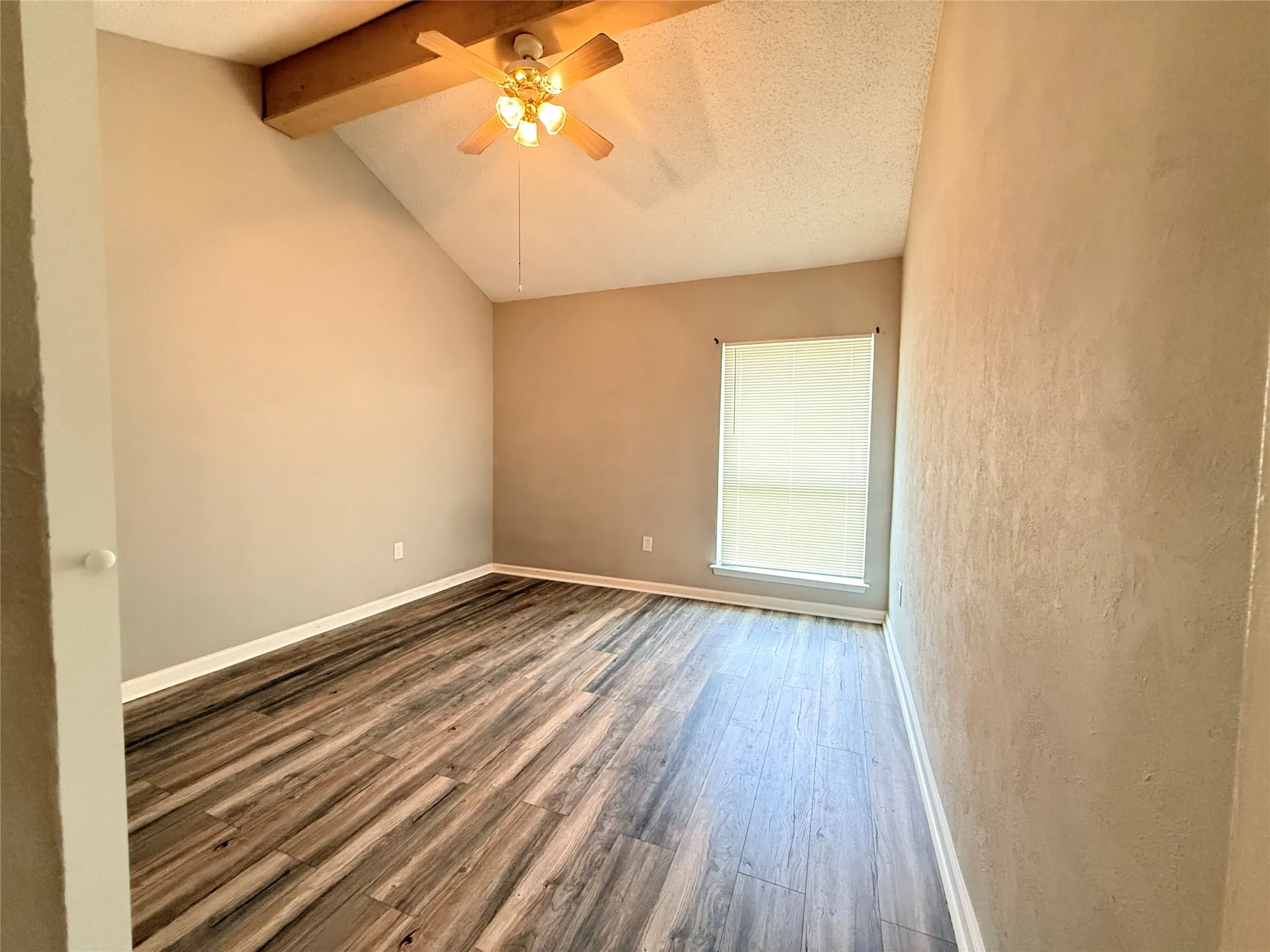 Vaulted ceiling with exposed wood beam and ceiling fan
