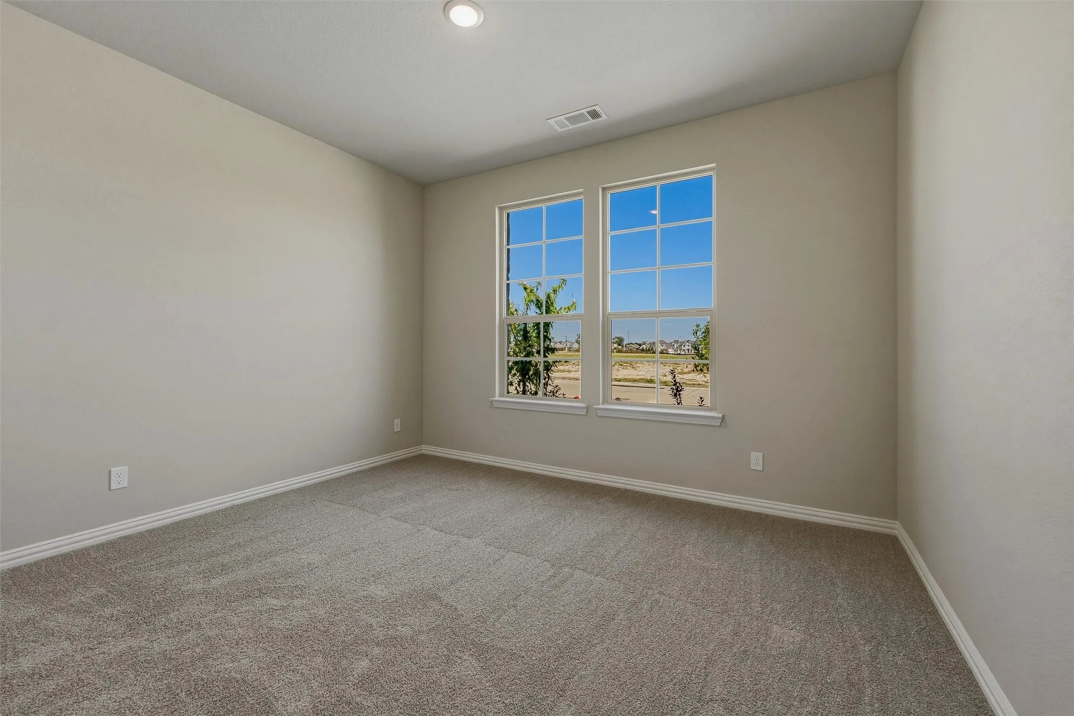 Neutral-toned walls with recessed lighting and gray carpeting