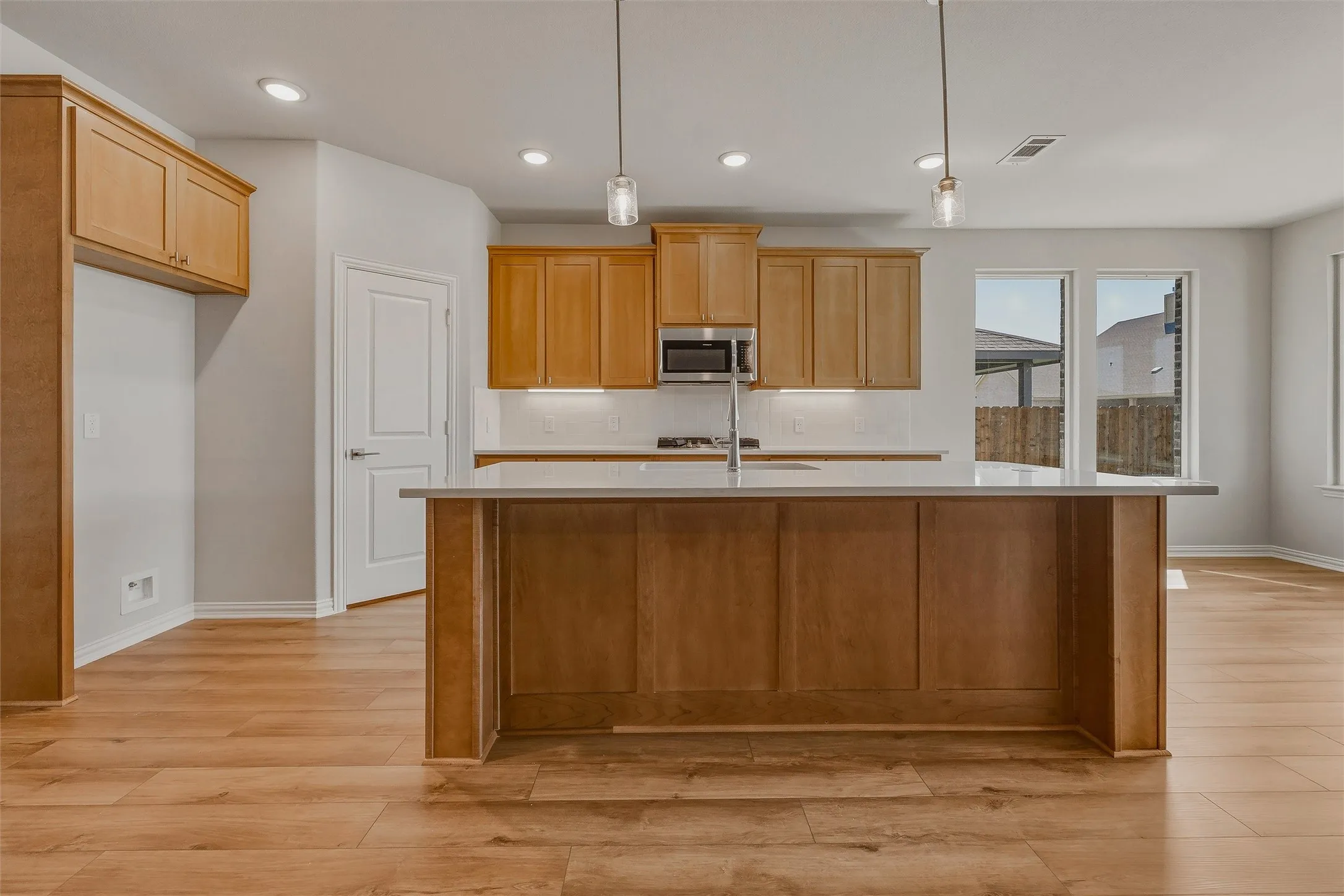 Kitchen featuring a central island with a light-toned countertop, wood-finish flooring, recessed lighting, and natural wood cabinetry