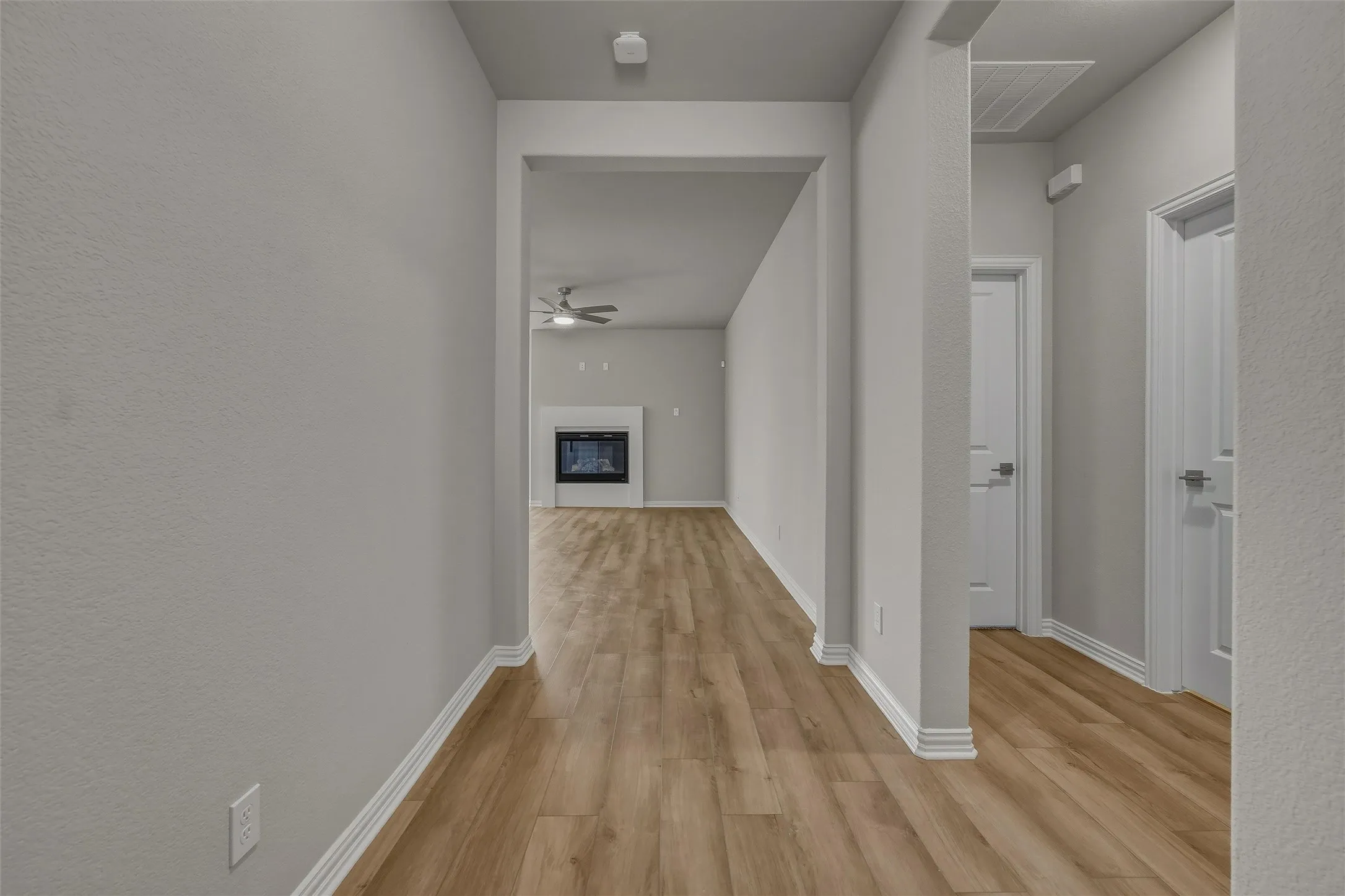 Wood-finish flooring throughout, bright walls, and a fireplace with a decorative mantel