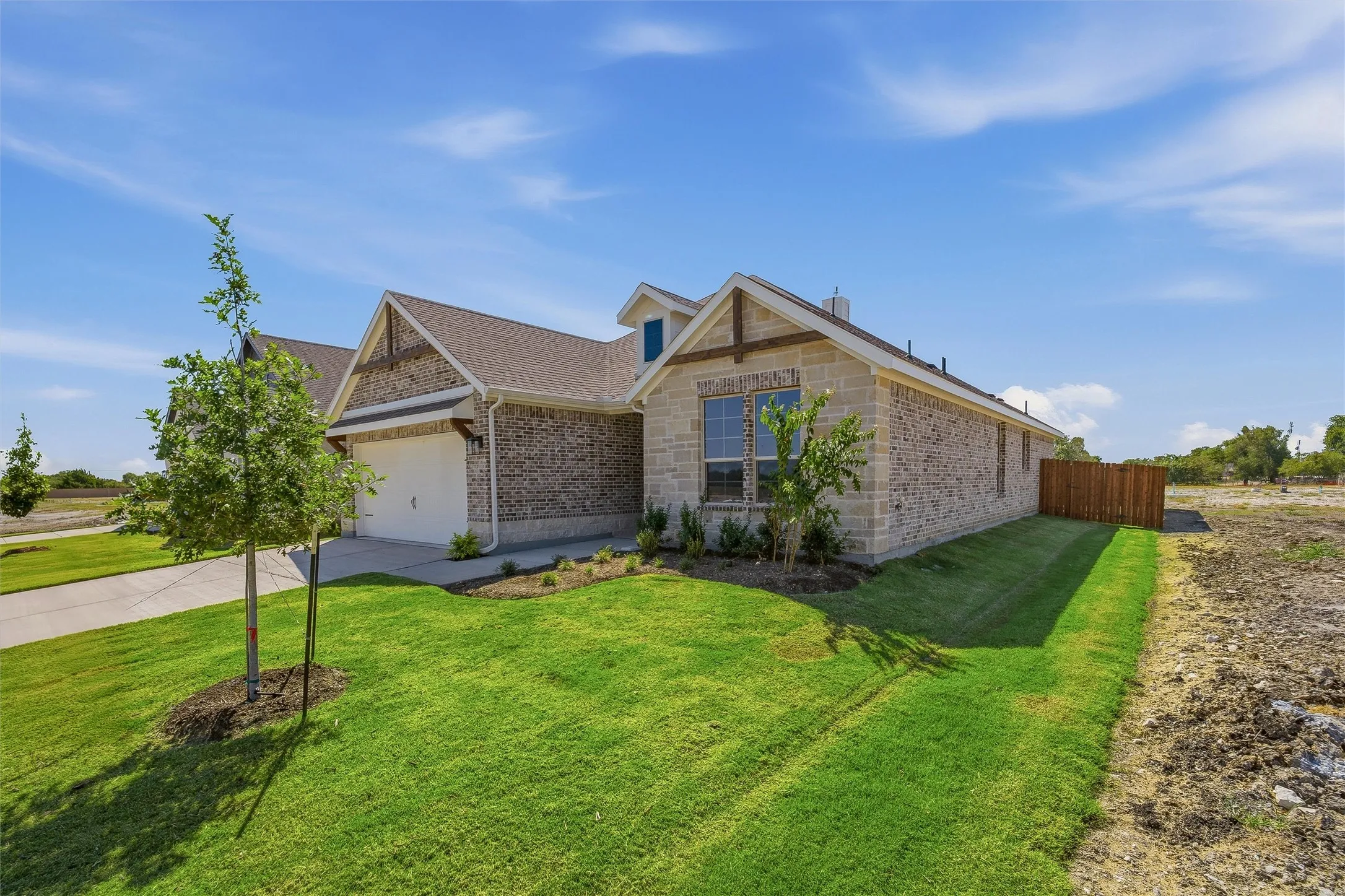 Brick exterior with stone accents, attached garage, well-maintained lawn, and a partial wood fence