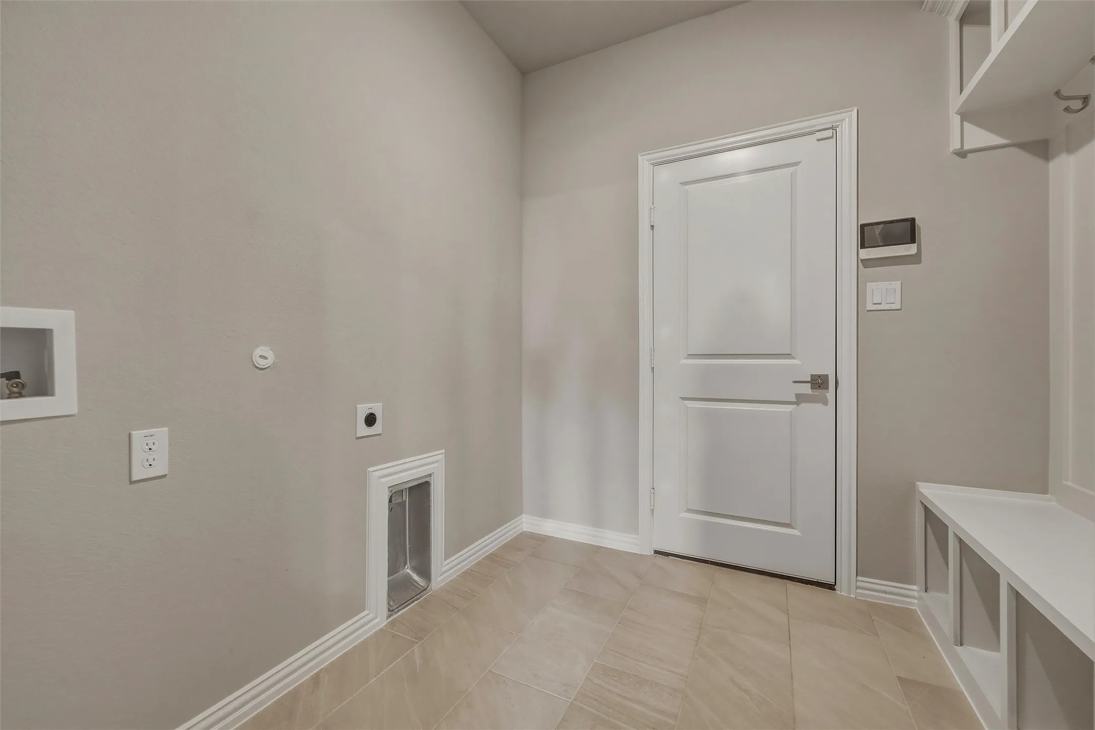Utility area featuring tile flooring, neutral wall paint, a built-in bench with storage, and integrated coat hooks