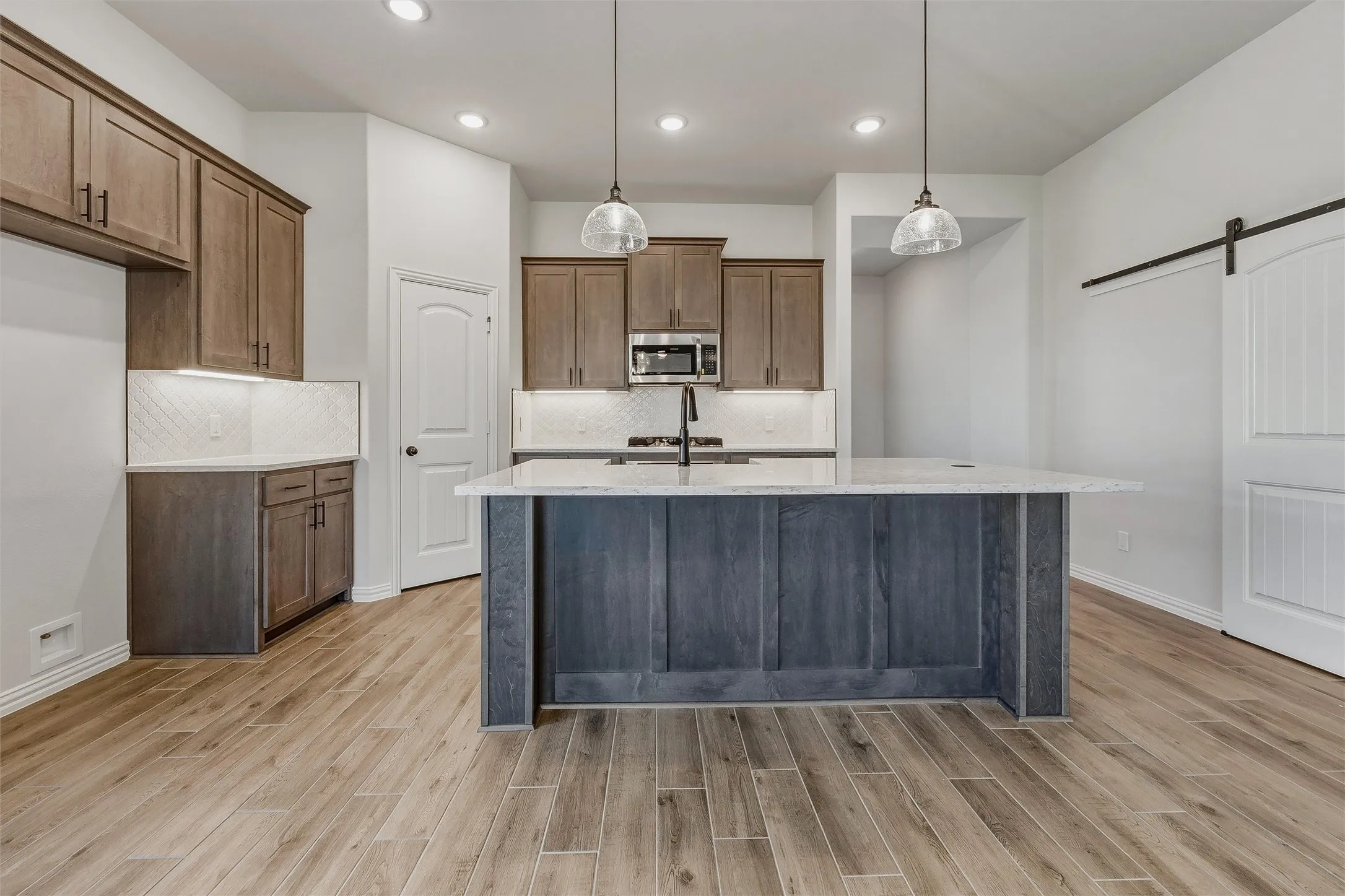 Kitchen featuring a central island, recessed lighting, wood-finish flooring, and a sliding barn door