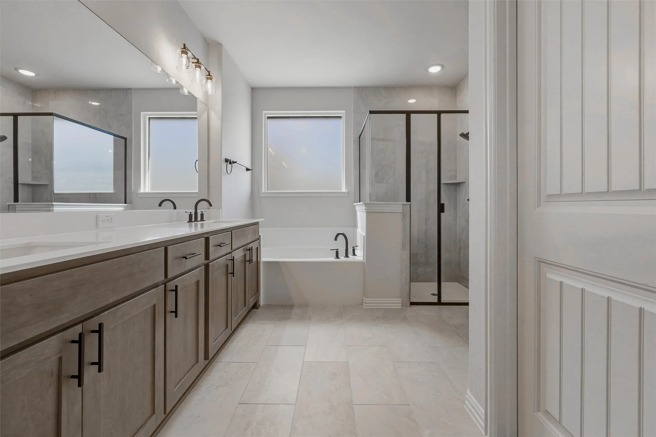 Dual vanity with white countertops, wood-finish cabinetry, and matte black fixtures