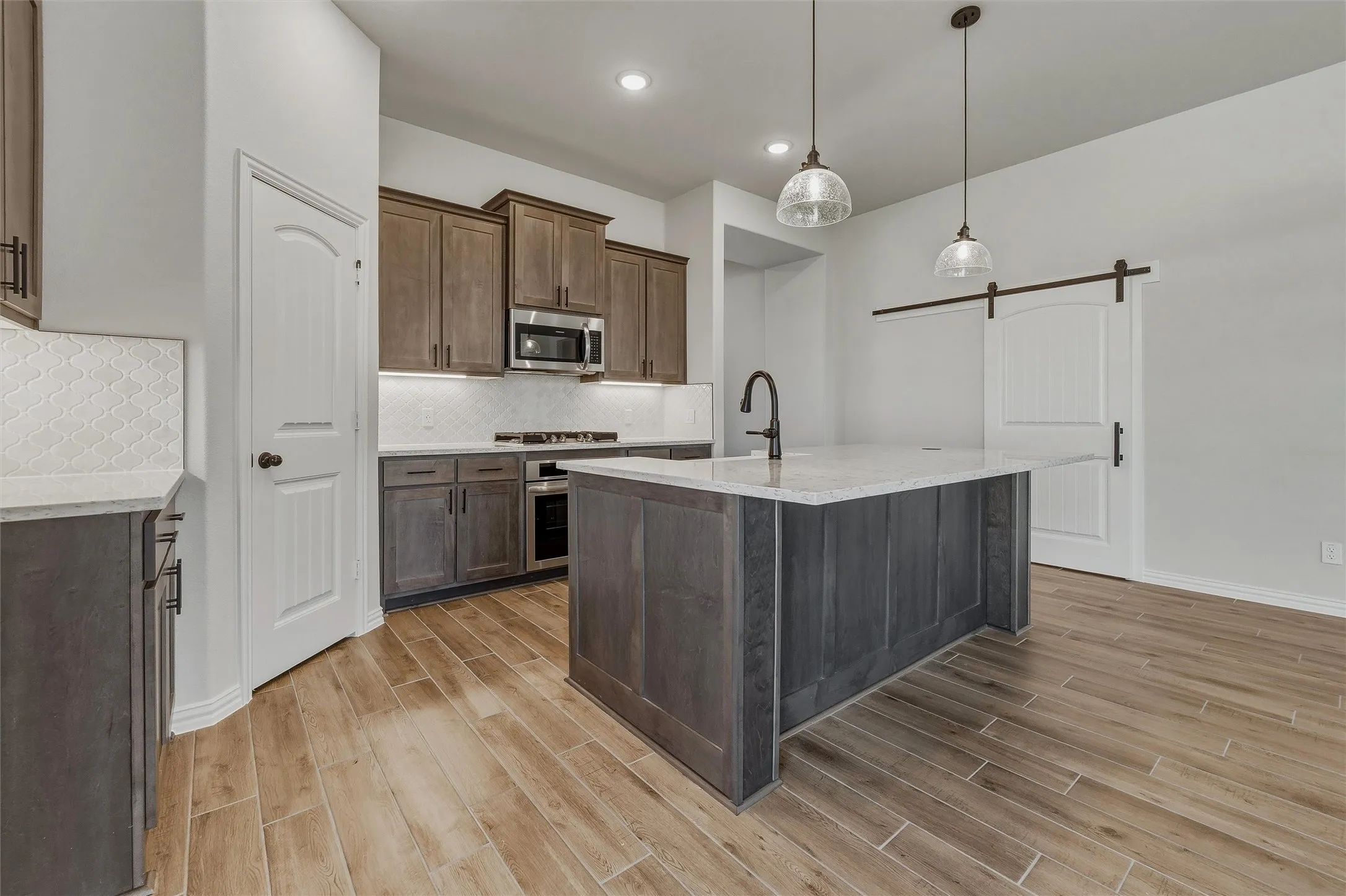 Kitchen featuring wood-finish flooring, a central island with countertop, coordinating cabinetry, and a sliding barn door