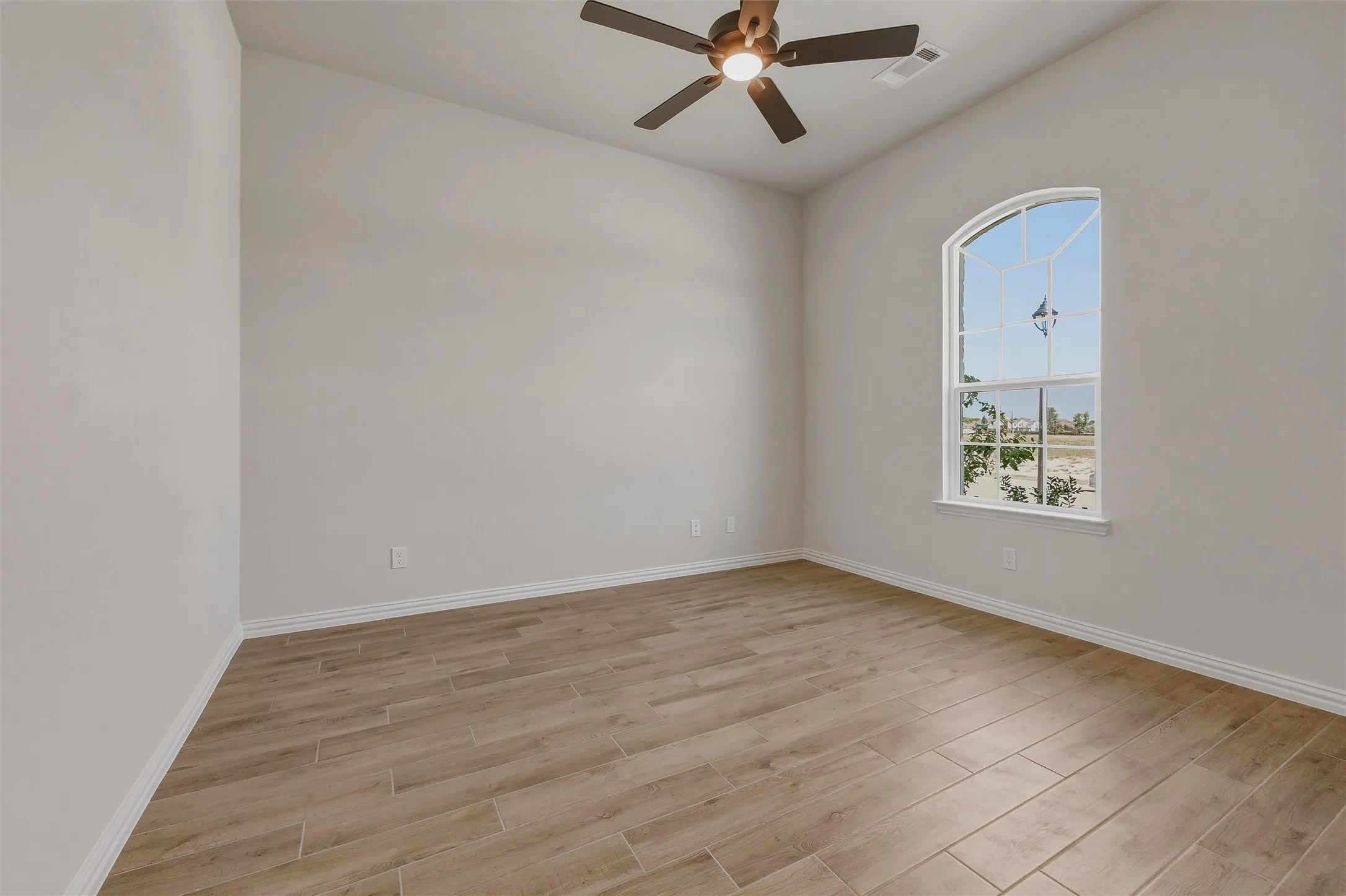 Vaulted ceiling, wood-finish flooring, arched window, and ceiling fan with integrated lighting