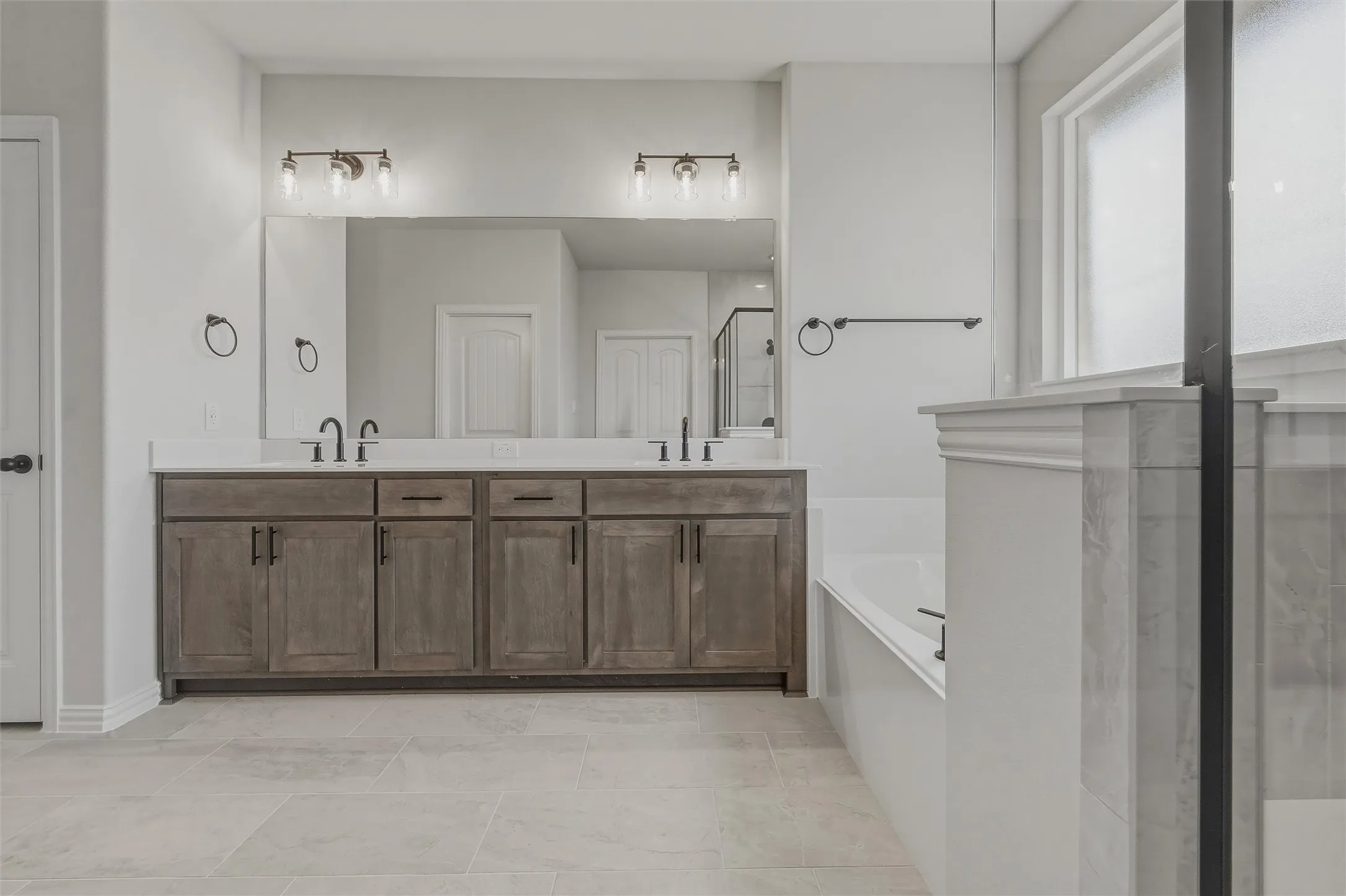 Dual vanity with wood-finish cabinetry, white countertops, and matte black fixtures
