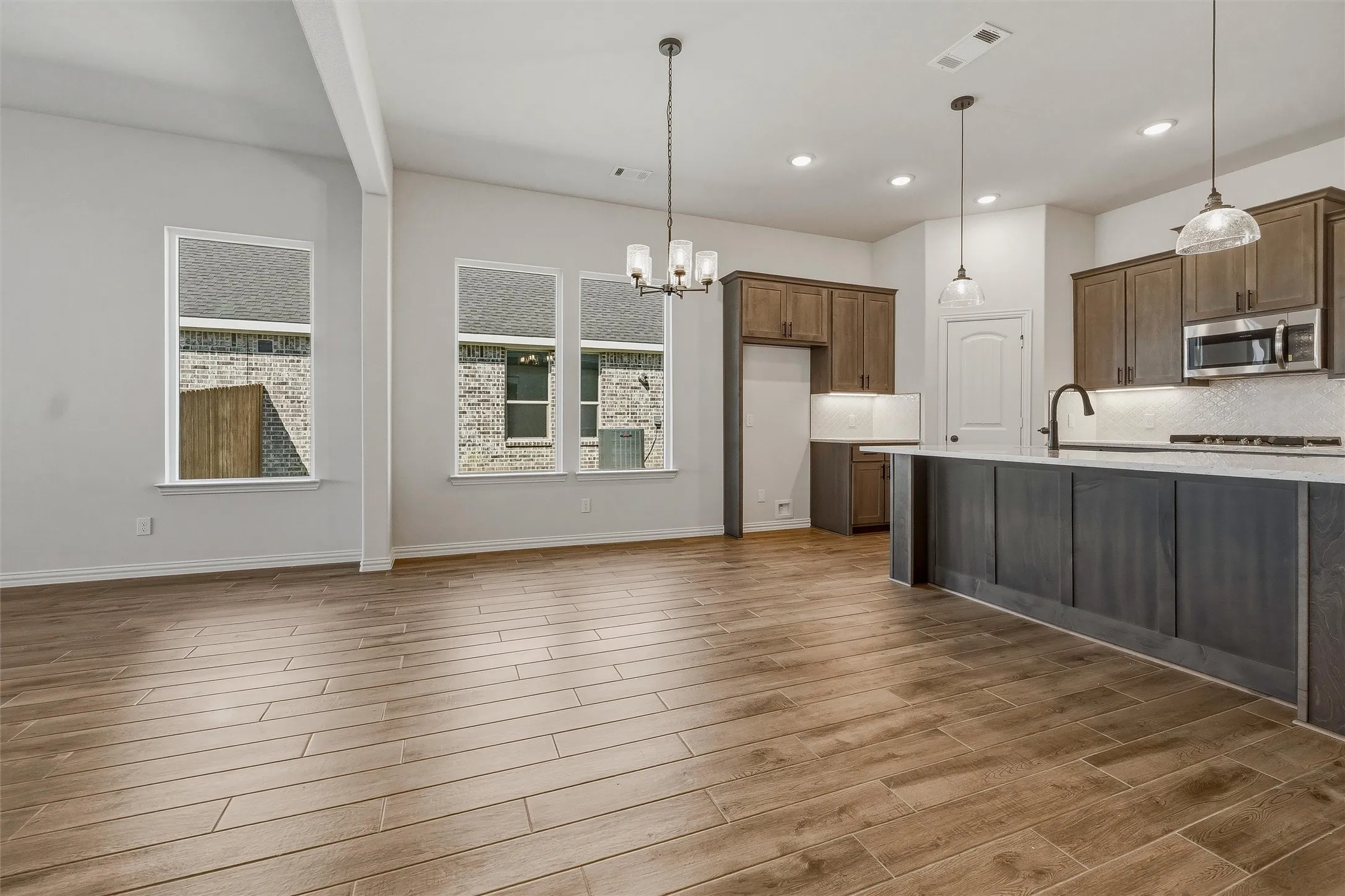 Open-concept floor plan featuring wood-finish flooring throughout, recessed lighting, and an island kitchen