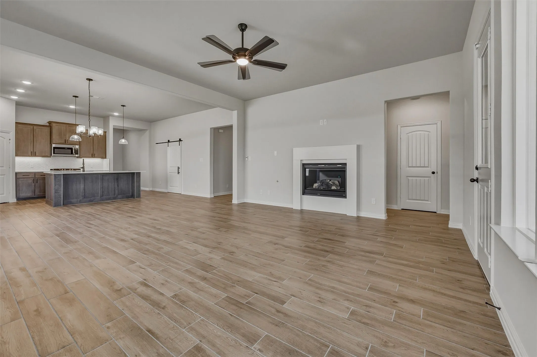 Wood-finish flooring, recessed lighting, and a modern ceiling fan in a spacious interior