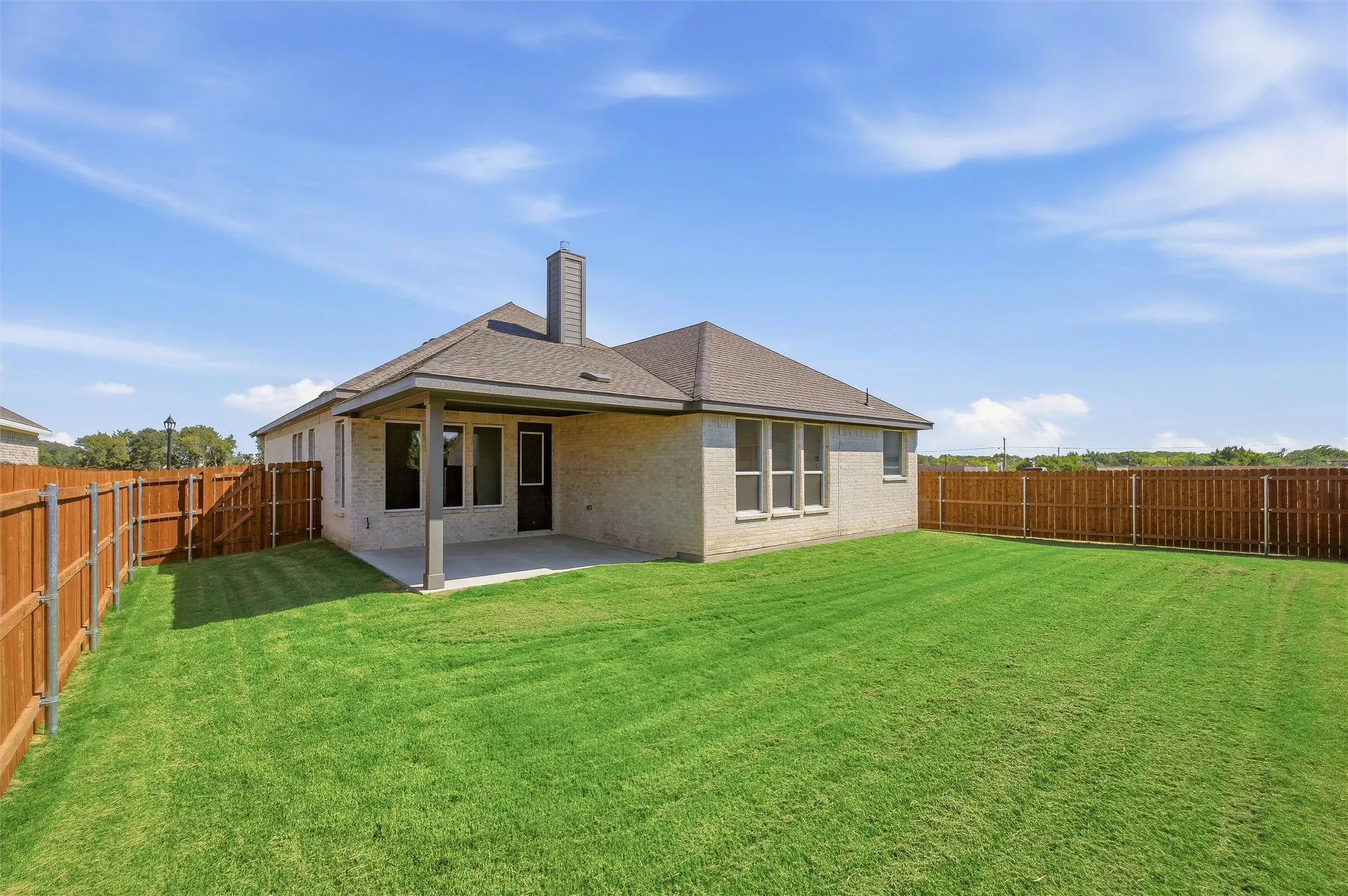 Expansive backyard featuring a covered patio, privacy fencing, and a stucco exterior