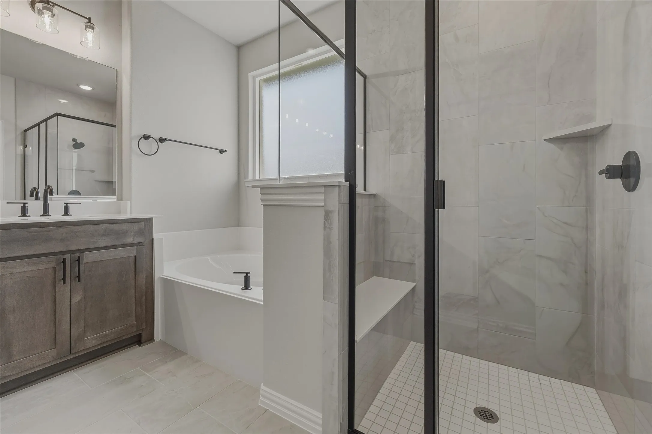 Walk-in shower with clear glass enclosure, integrated bench, and tiled walls