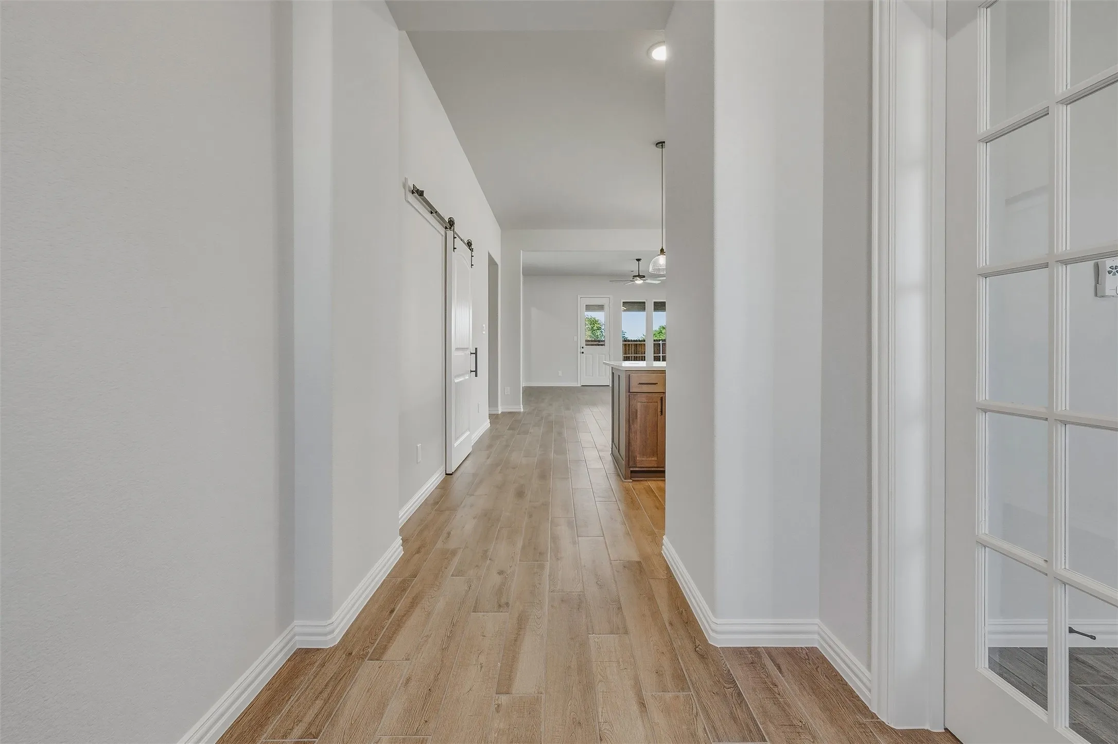 Wood-finish flooring throughout, white walls, and a barn door with black hardware