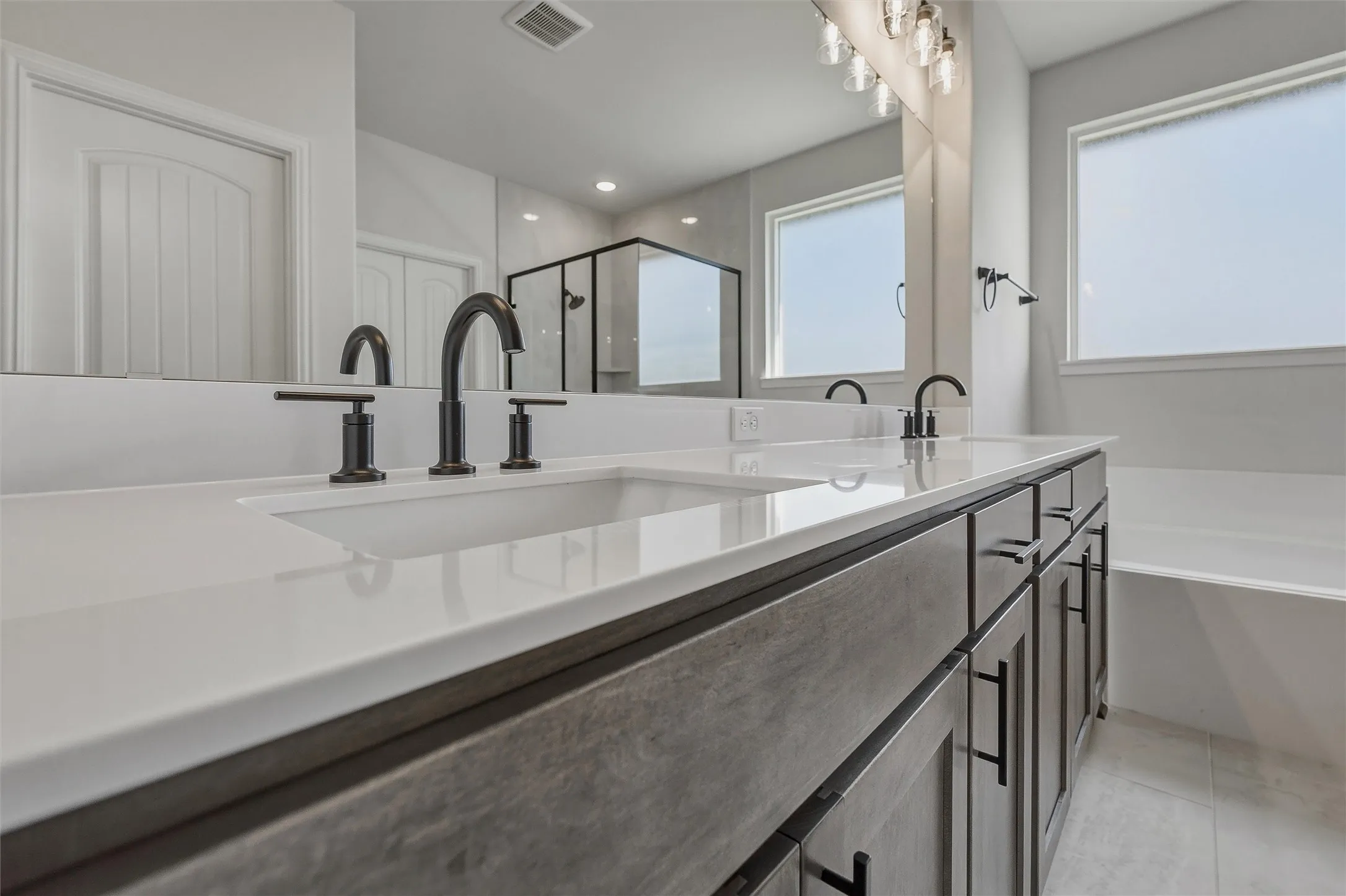 Dual vanity with white solid surface countertops, integrated sinks, and matte black fixtures