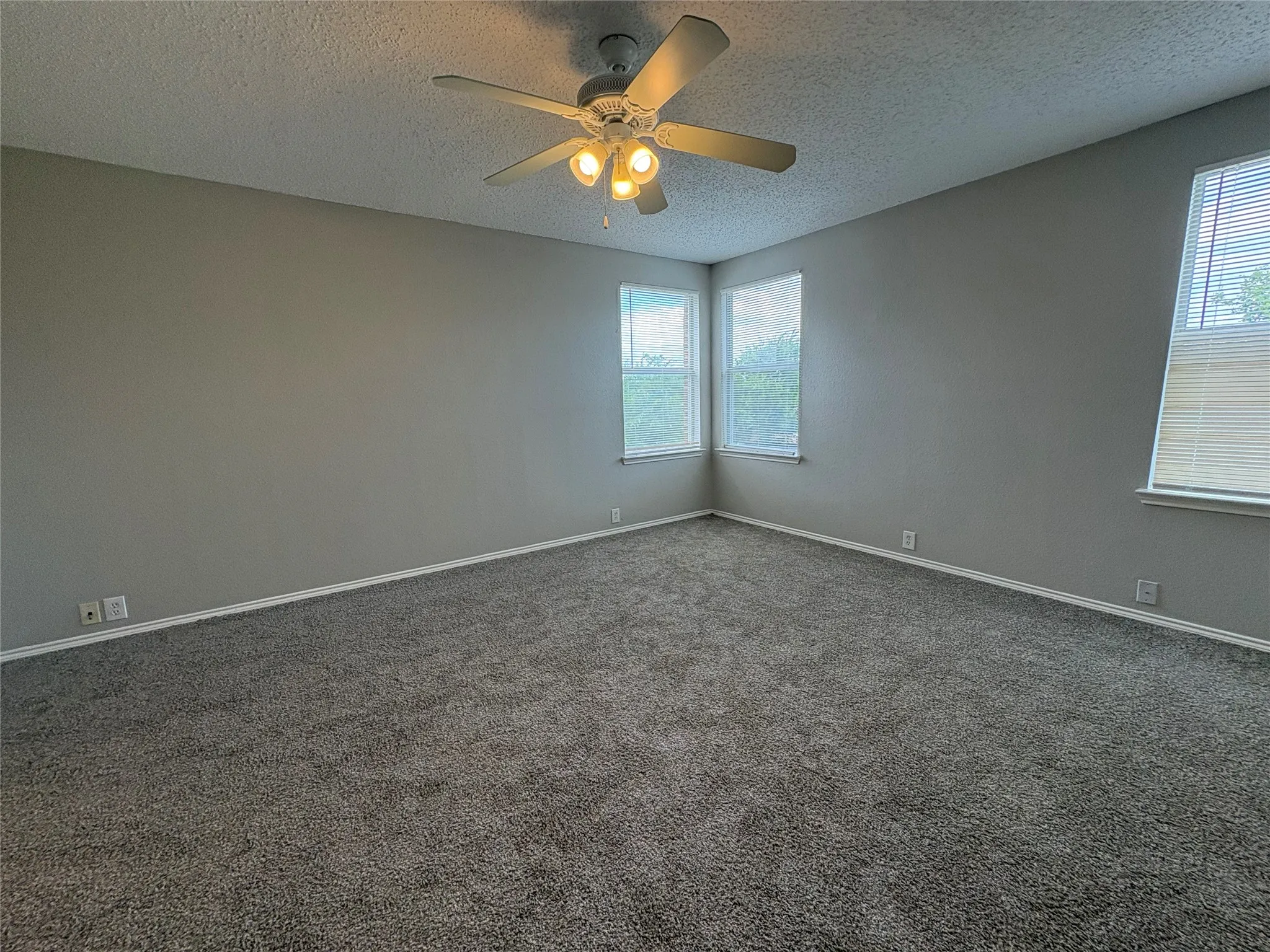 Spacious room featuring neutral grey walls and new carpet