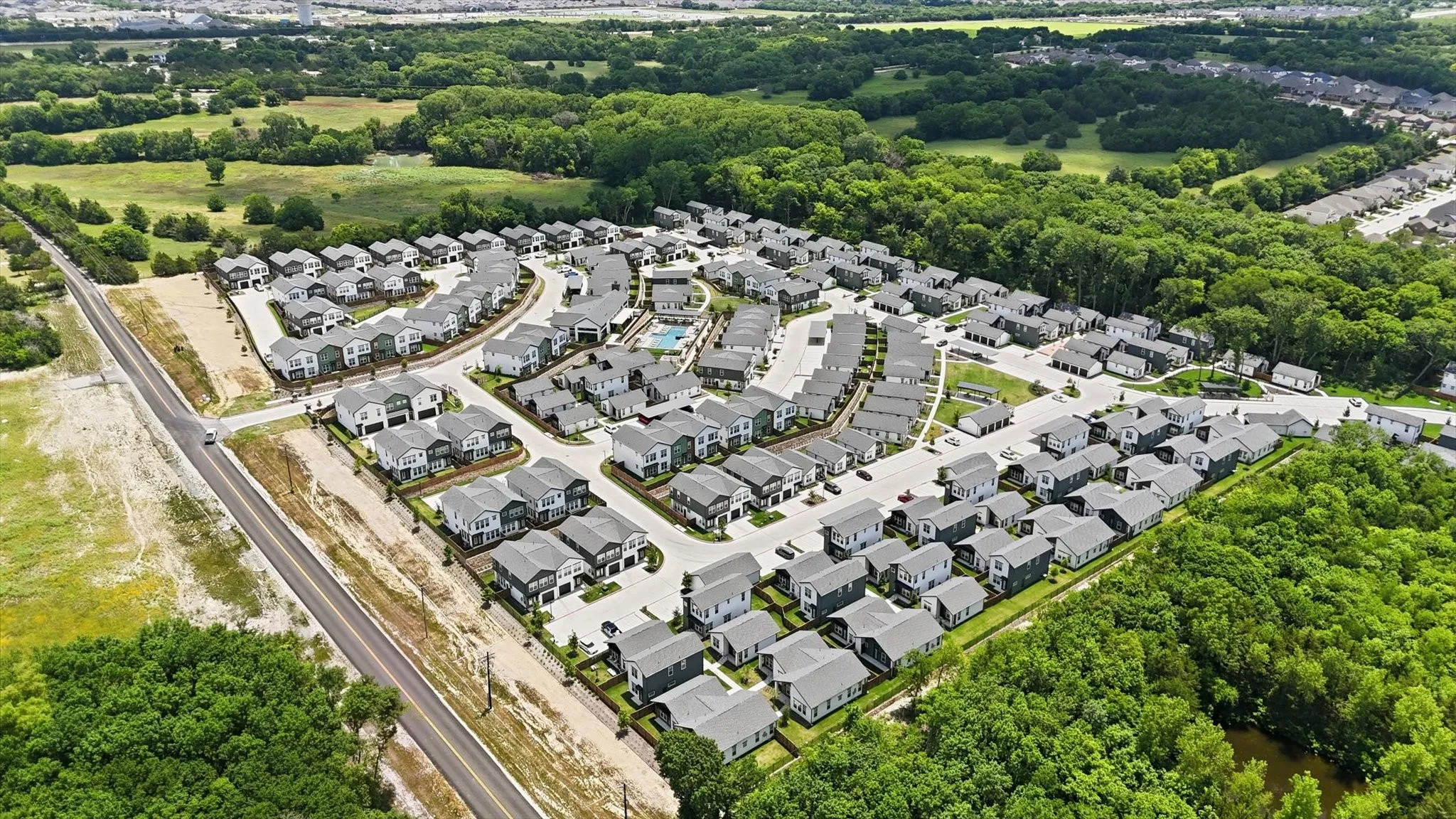 Aerial perspective of a developed residential community featuring multiple two-story homes, an integrated road network, and a central amenity area