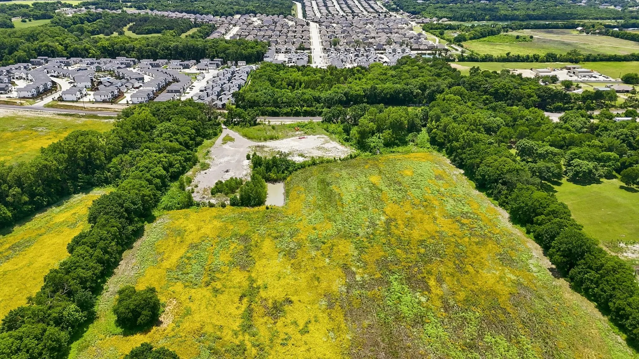 Expansive land parcel featuring open fields and mature tree lines