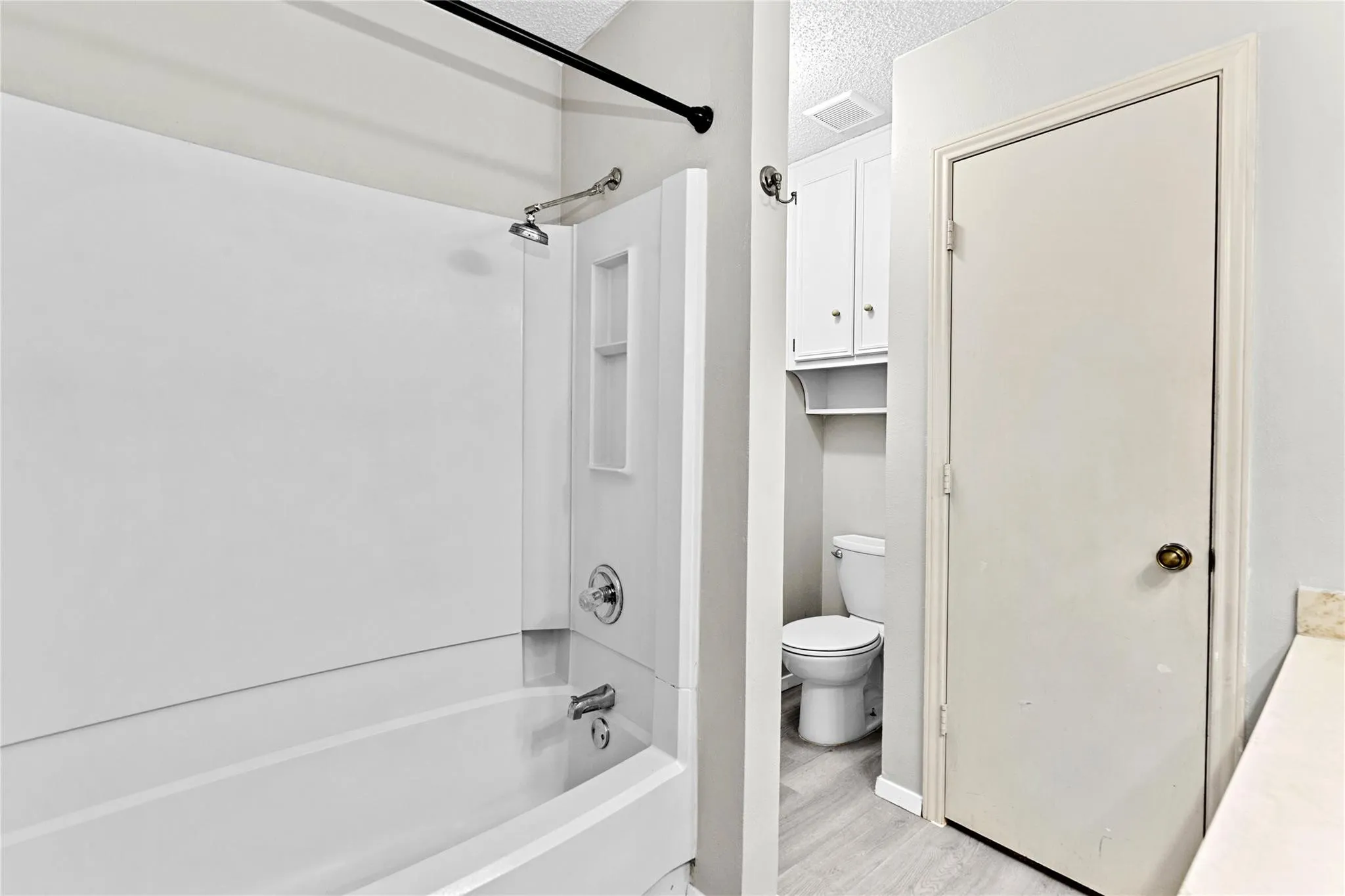 White tub and shower combination with chrome fixtures and an integrated shower niche