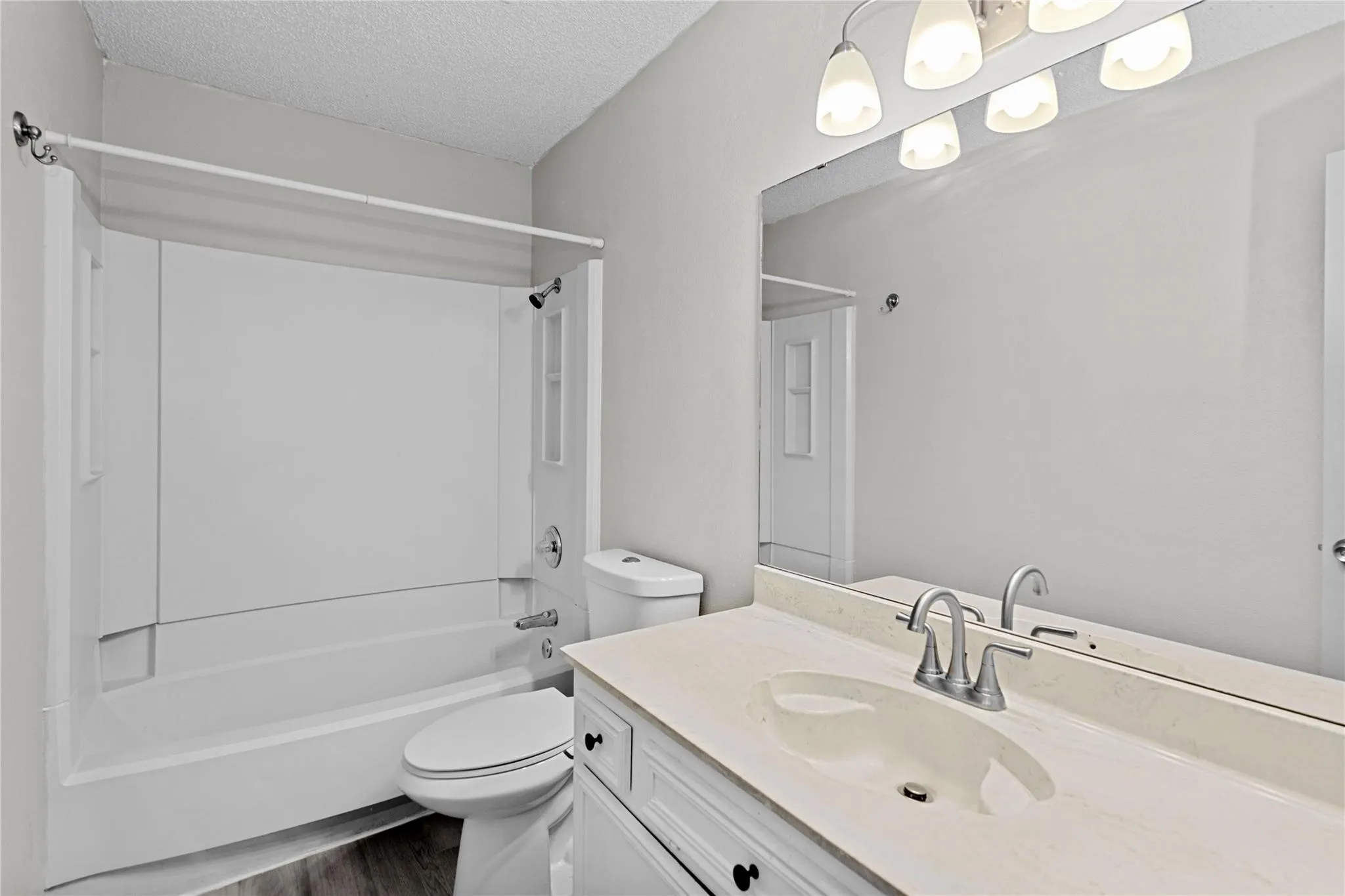 Bathroom featuring a white vanity with an integrated sink, a large wall-mounted mirror, and a sleek light fixture