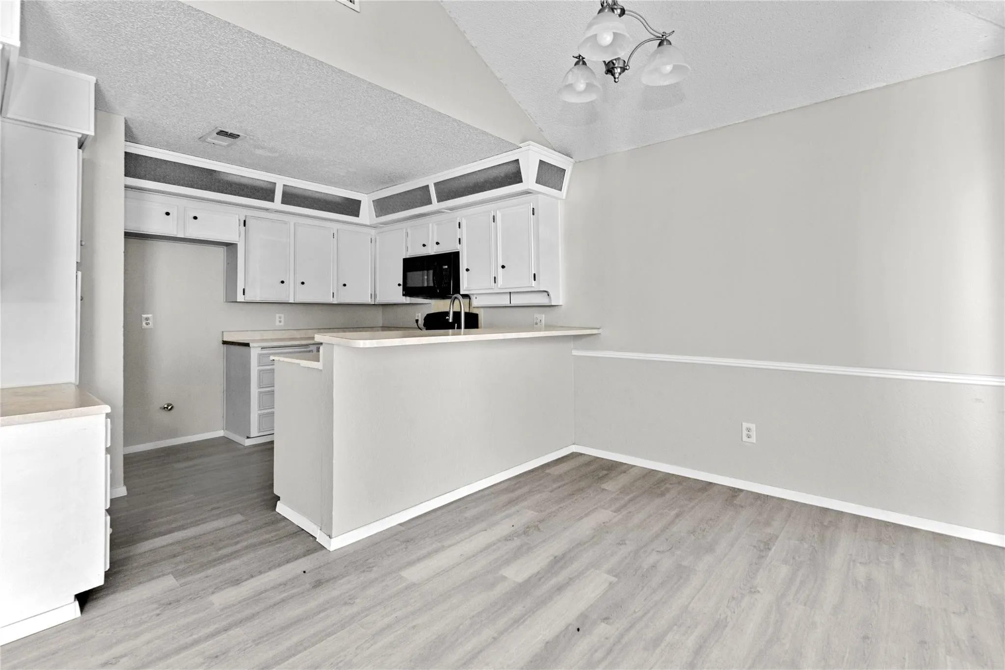 Kitchen area featuring light wood-finish flooring and a vaulted ceiling