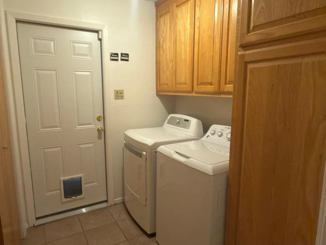 Functional utility space featuring wood cabinetry, tiled flooring, and a white paneled door