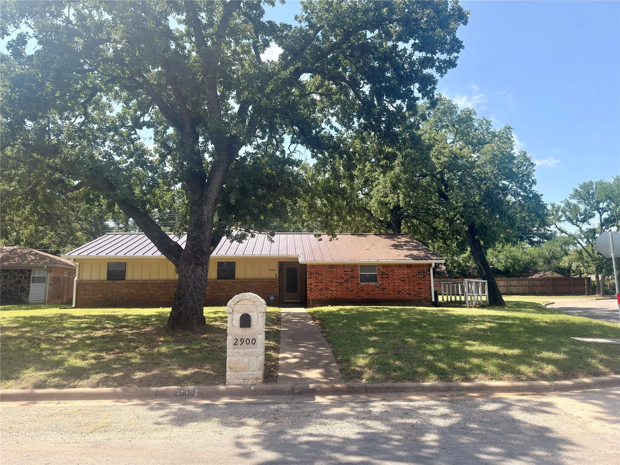 Single-story residence featuring a brick and siding exterior, a metal roof, and a stone mailbox