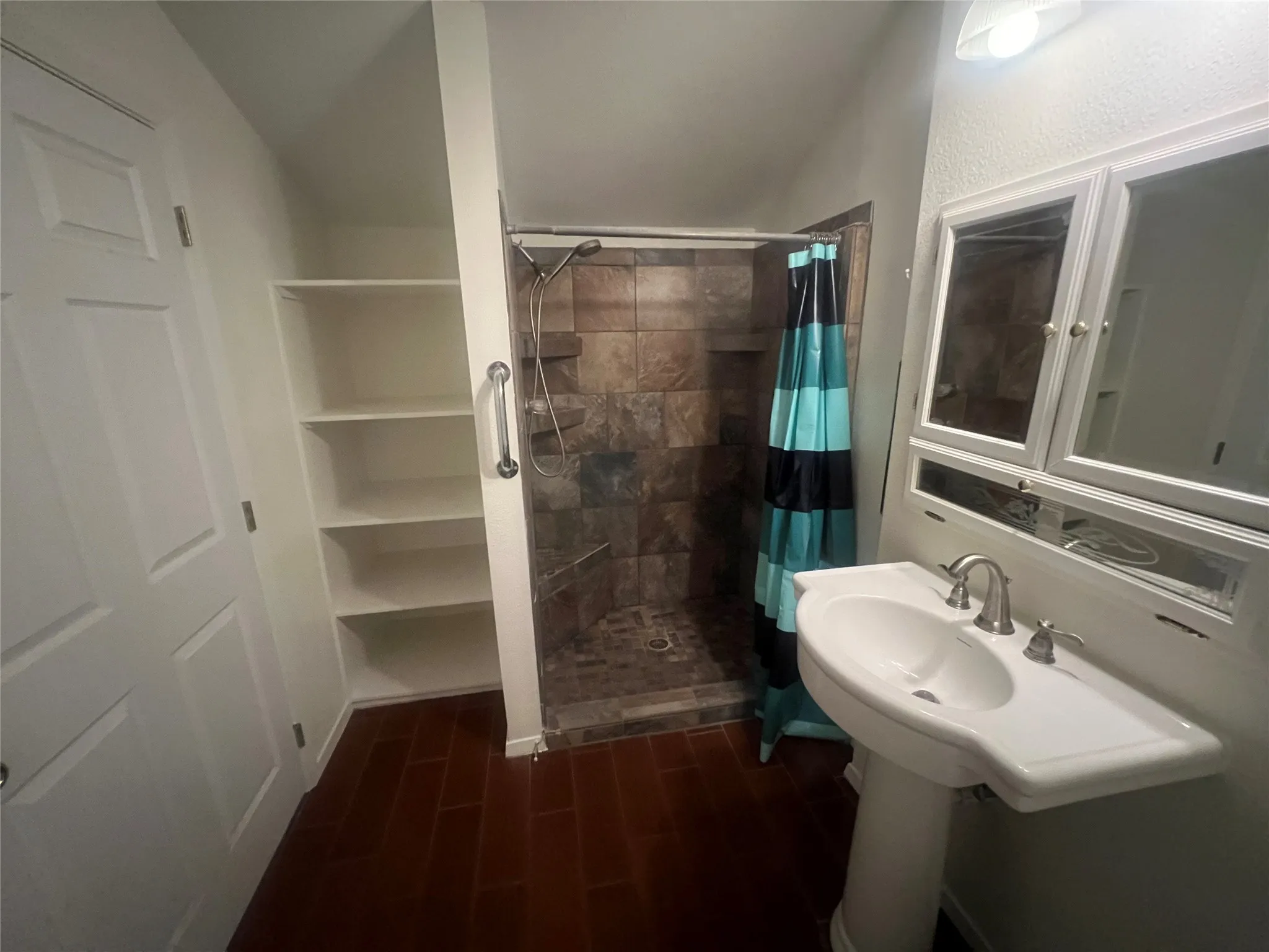 Pedestal sink with dual-handle faucet, medicine cabinet, and overhead lighting