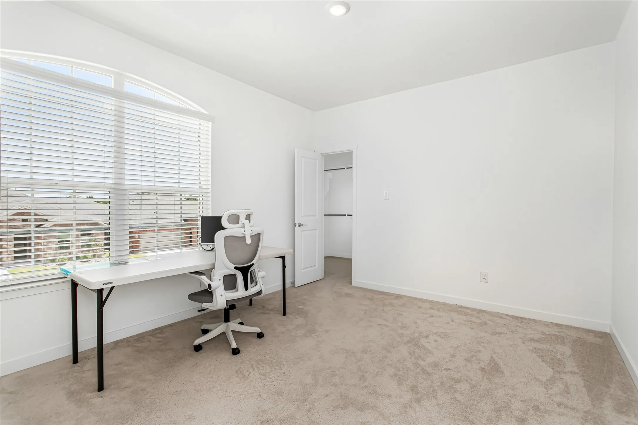 Carpeted 2nd floor bedroom featuring a large arched window with blinds, a recessed ceiling light, and a white interior door