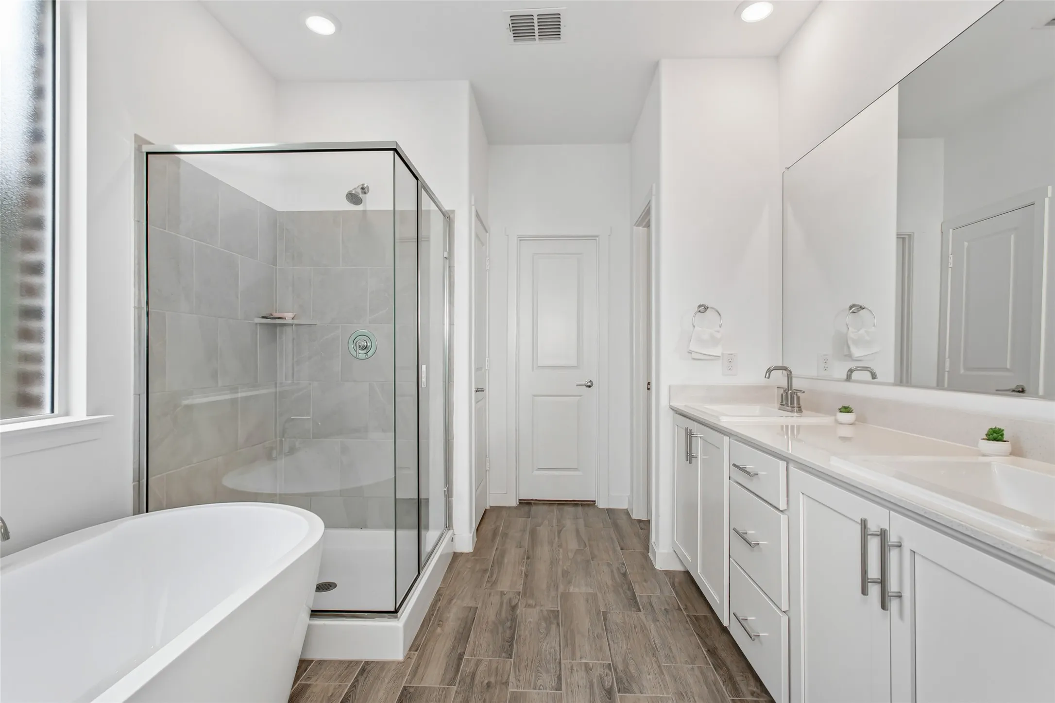Modern bathroom featuring wood-finish flooring and a freestanding soaking tub