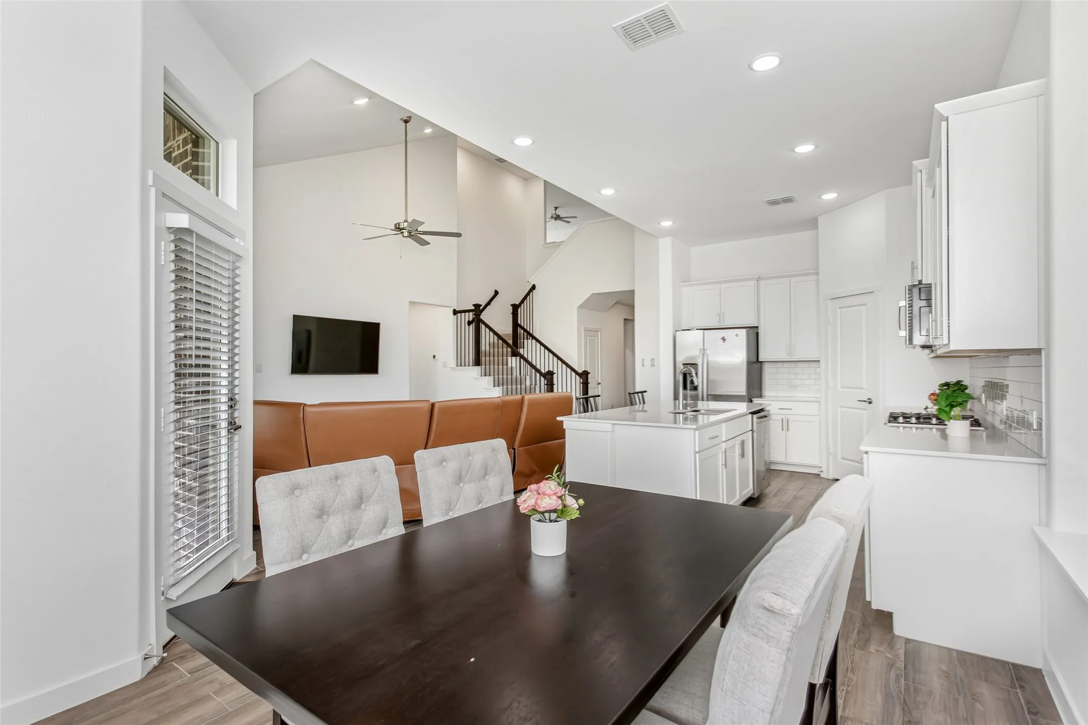 Open-concept living area featuring a kitchen with white cabinetry and stainless steel appliances, a center island, and wood-finish flooring