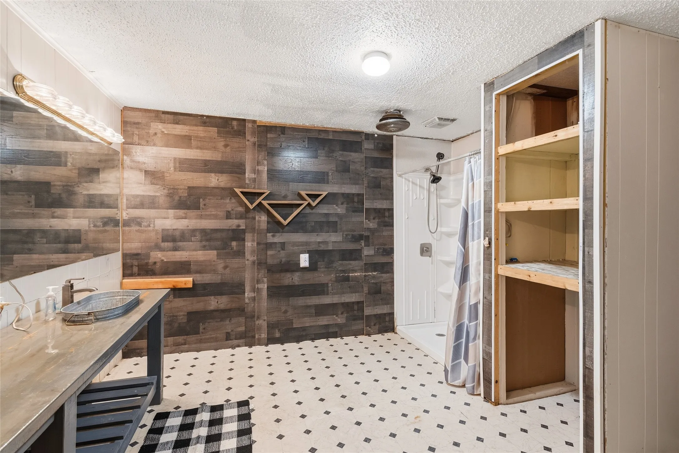 Bathroom featuring a wood-finish accent wall, built-in shelving, white shower enclosure, and checkerboard floor tiles