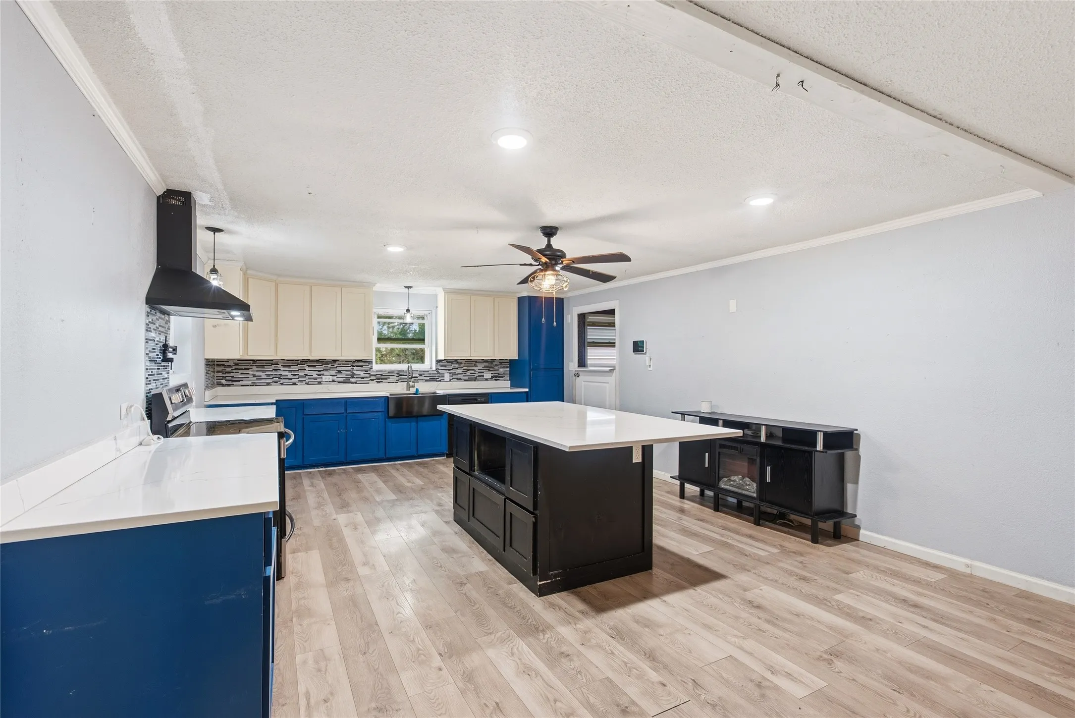 Open-concept kitchen and living area featuring wood-finish flooring, recessed lighting, and a ceiling fan