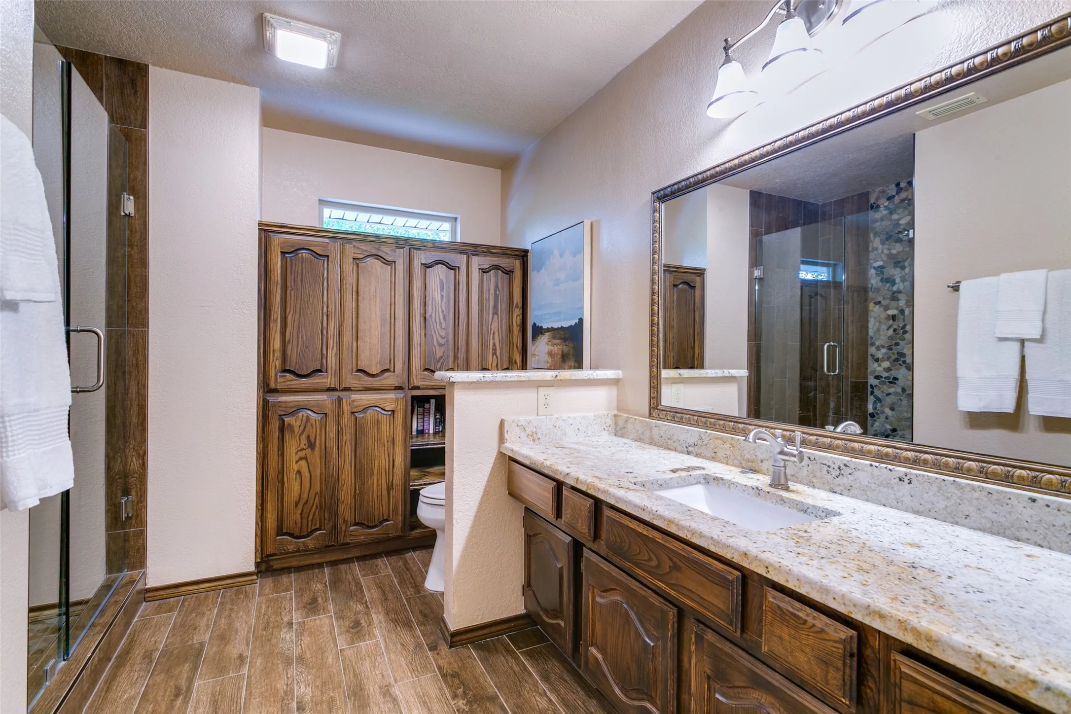 Updated 3rd full bath features granite counters, wood-look ceramic tile, and built-in cabinets