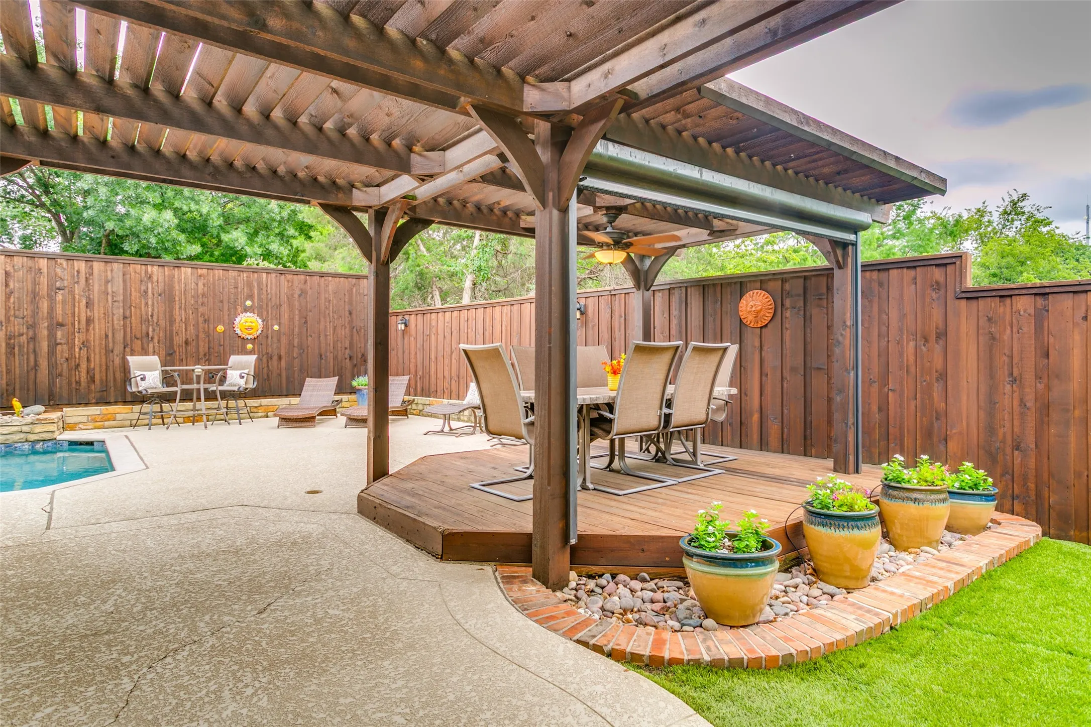 Pergola-covered dining space with a motorized shade offers the perfect setting for outdoor meals and entertaining