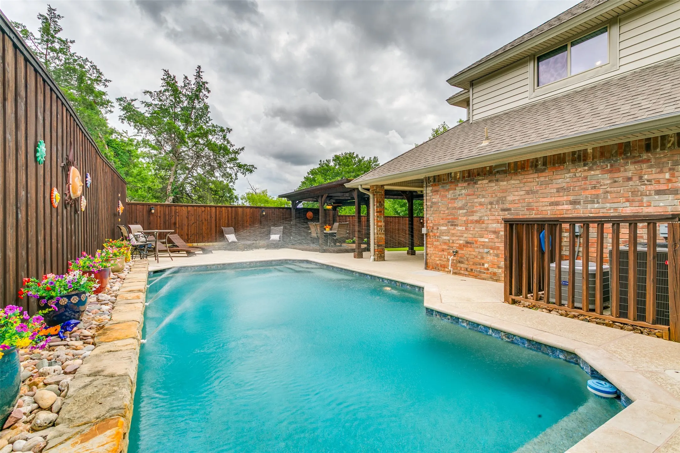Exceptional outdoor living combines a pool, covered patio, outdoor kitchen, and a pergola-covered dining area