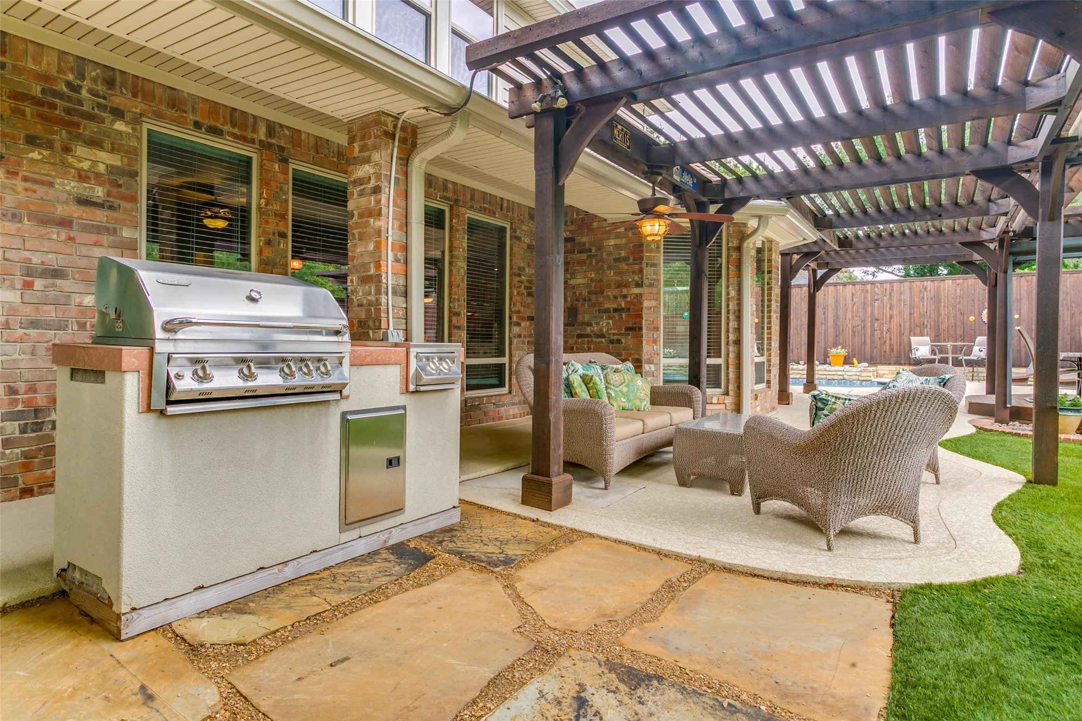 Covered outdoor living area with plumbed gas grill, seating area and views of the pool