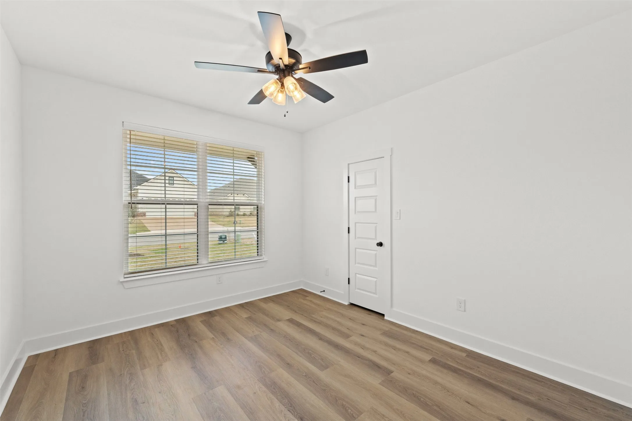 Bright room featuring a multi-light ceiling fan, a window with horizontal blinds, and wood-finish flooring