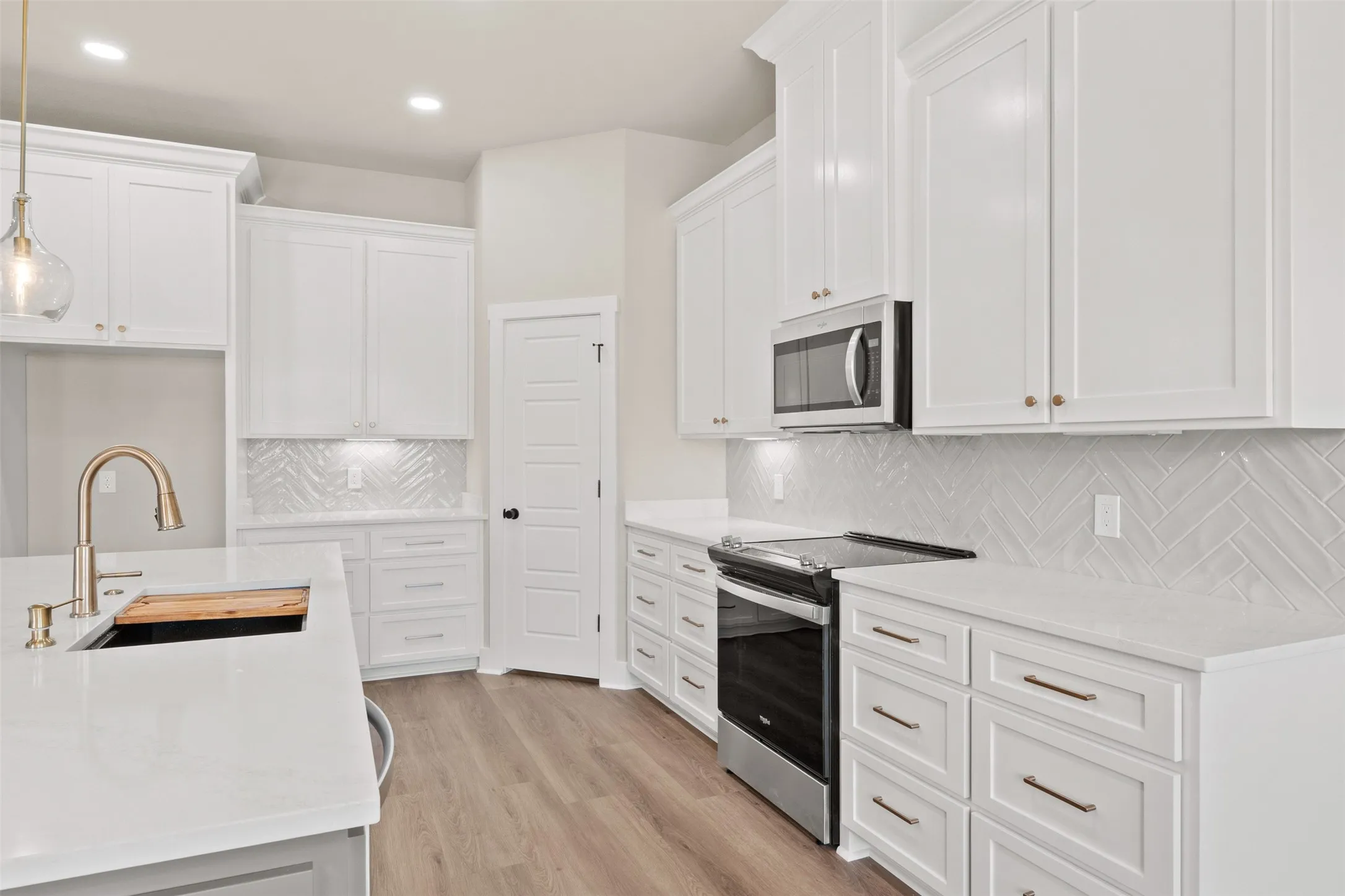 Kitchen featuring white shaker cabinetry, light wood-finish flooring, white countertops, and a herringbone tile backsplash